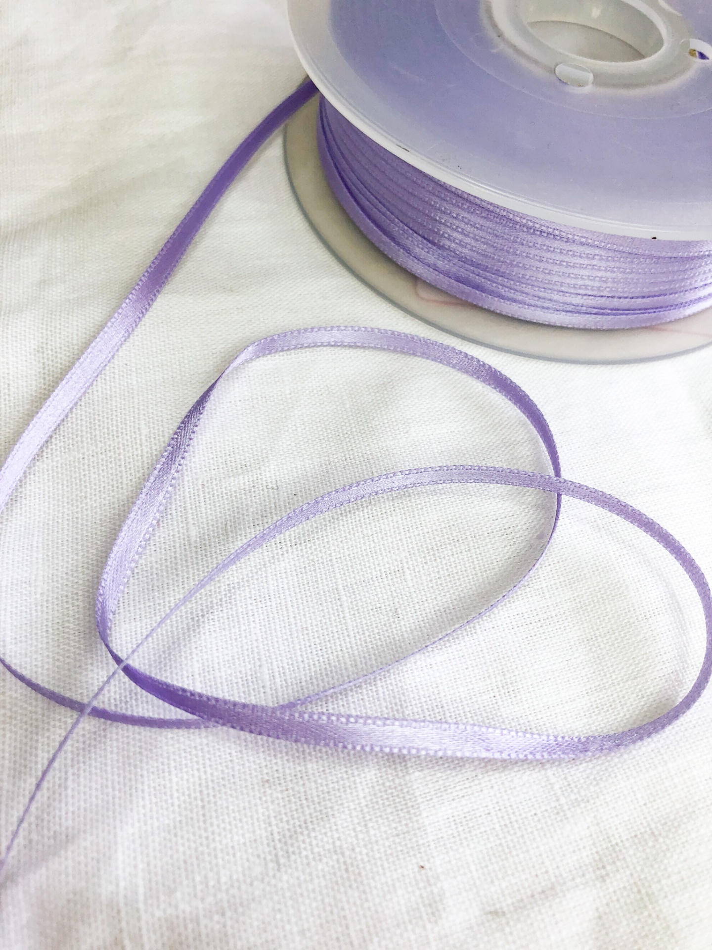 Rolo de fita fina roxa em tecido acetinado com fita em forma de coração