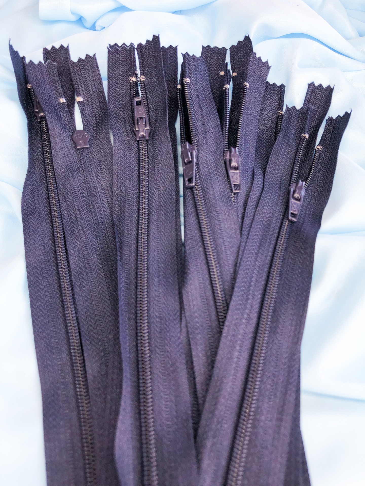 Fechos éclair pretos com puxadores de metal sobre tecido azul claro