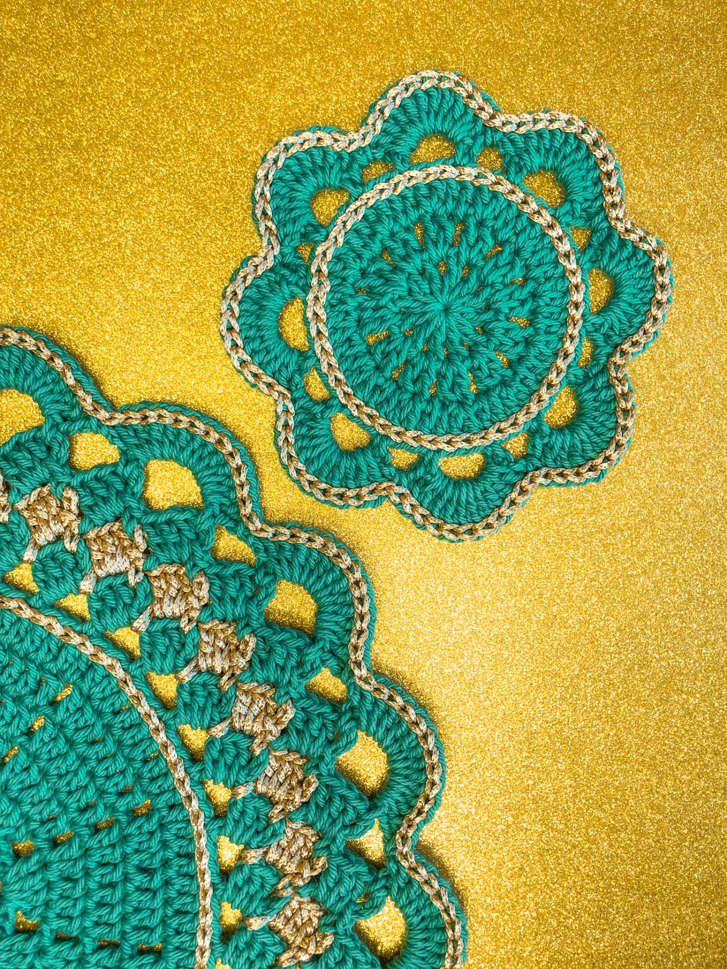 Dois tapetes redondos de croché verde e bege sobre fundo dourado