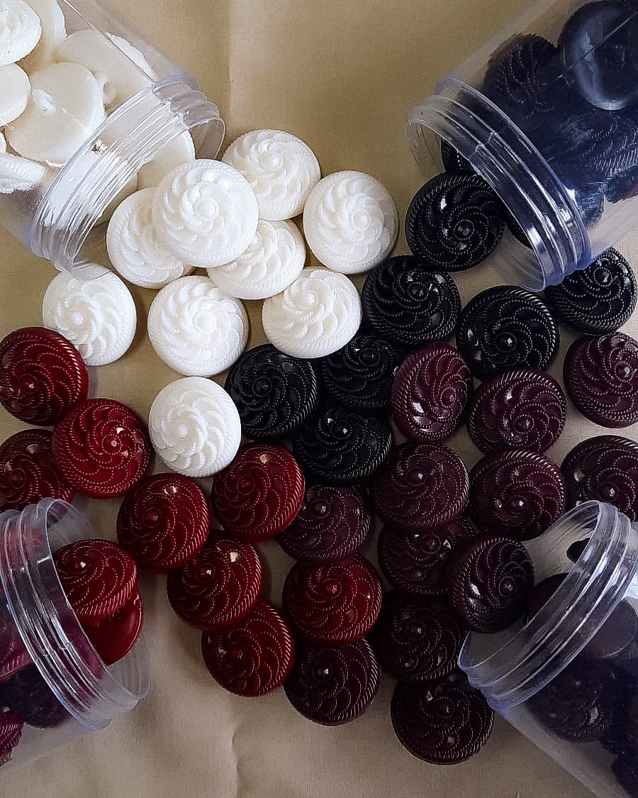 botões redondos decorativos em branco, preto e vermelho em frascos transparentes