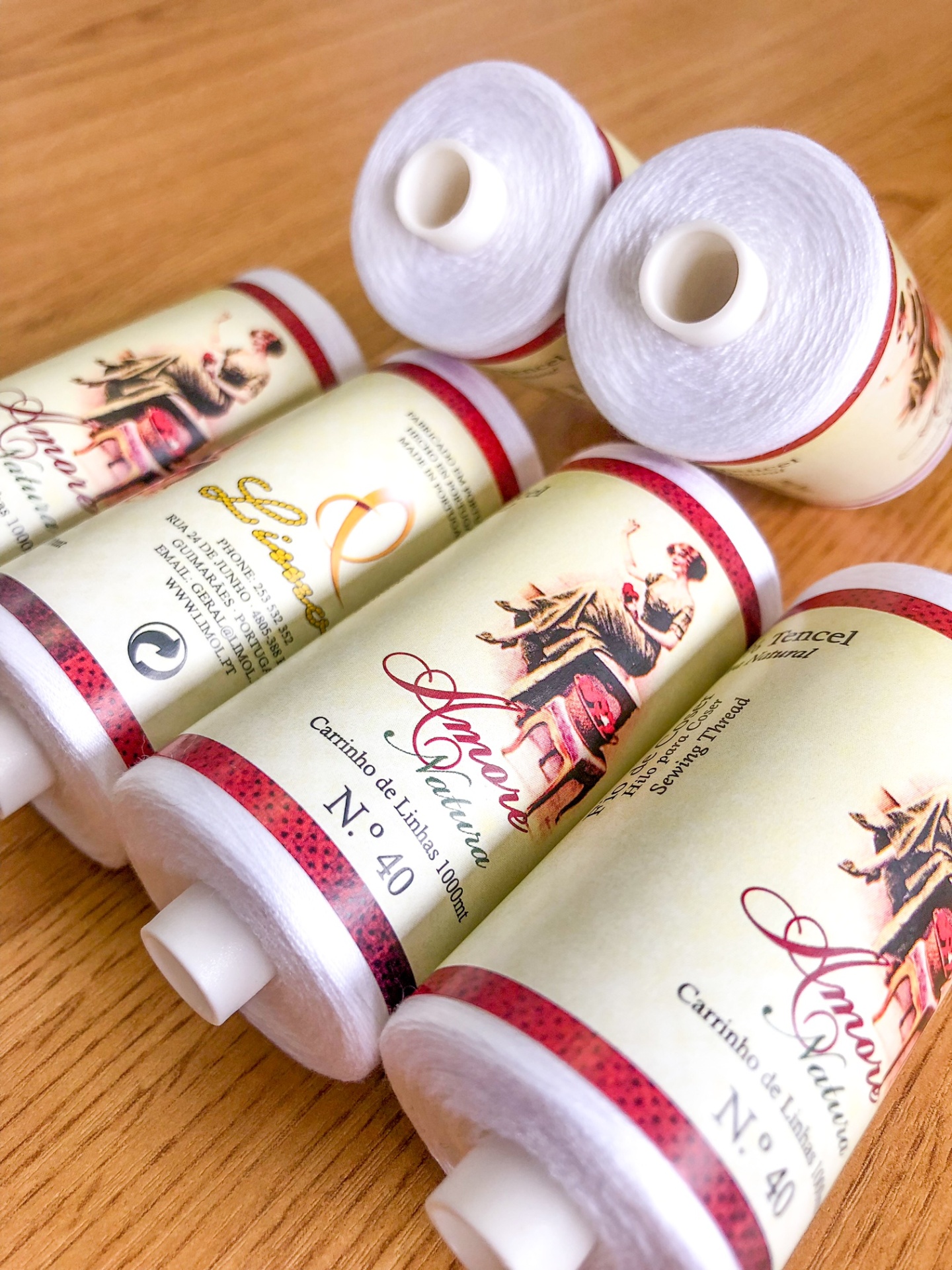 Cinco cones de linha branca com rótulos ilustrados sobre superfície de madeira