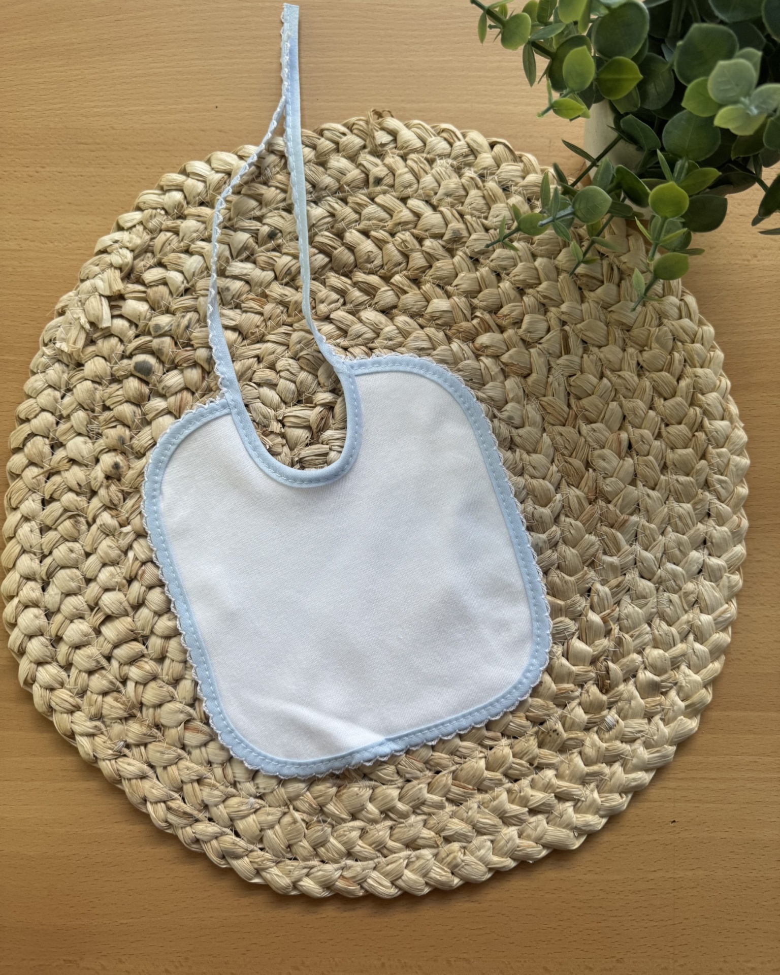 Babete branco com borda azul sobre tapete de fibra natural redondo