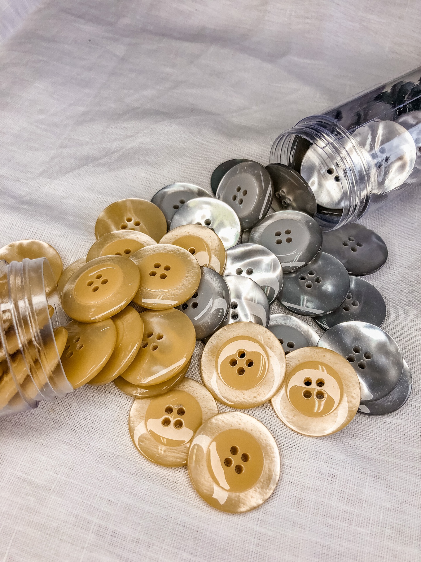 Botões redondos bege, pérola e cinza em tecido branco