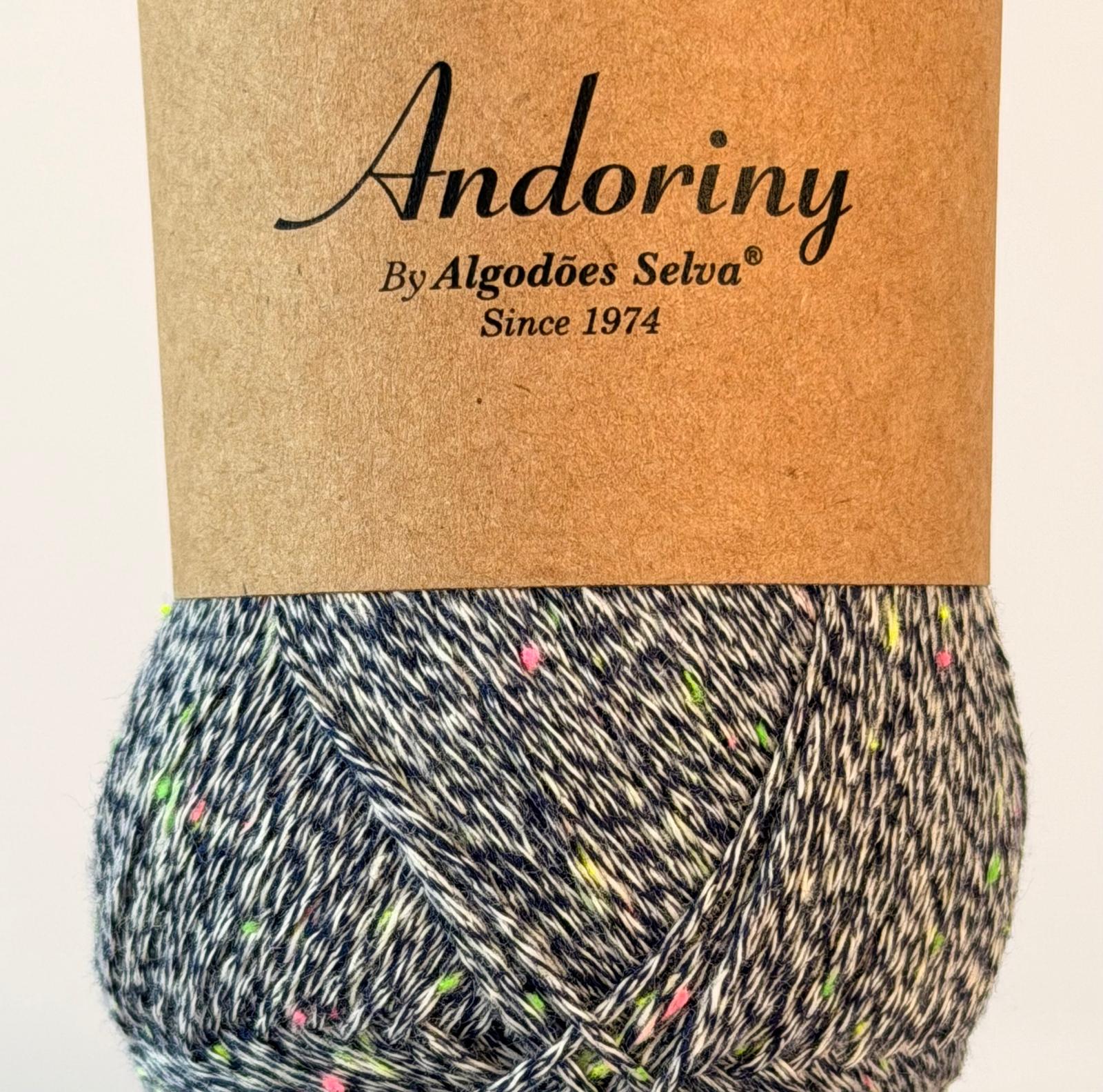 Novelo de lã preto e branco com pontos coloridos e rótulo castanho com texto Andoriny By Algodões Selva Since 1974
