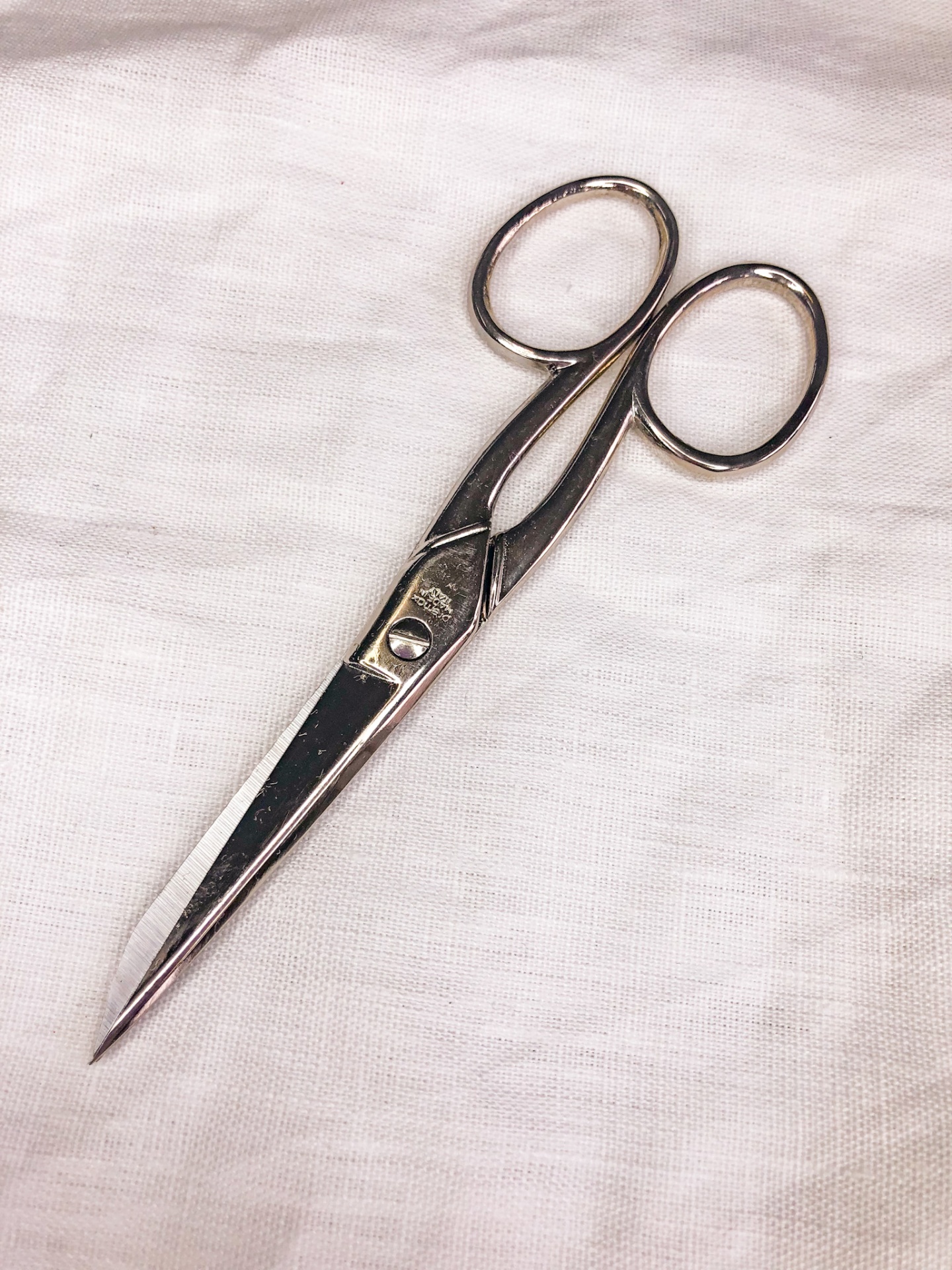 Tesoura metálica prateada sobre tecido branco texturizado