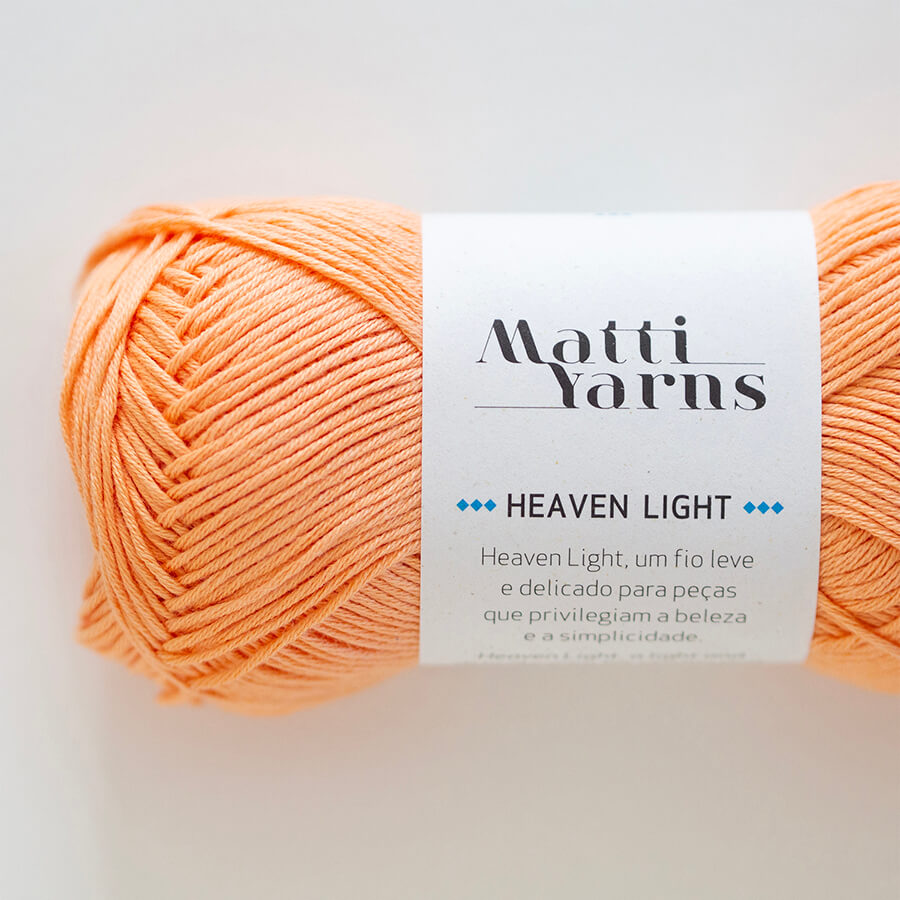 Novelo de fio de lã laranja claro com etiqueta branca da marca Matti Yarns Heaven Light