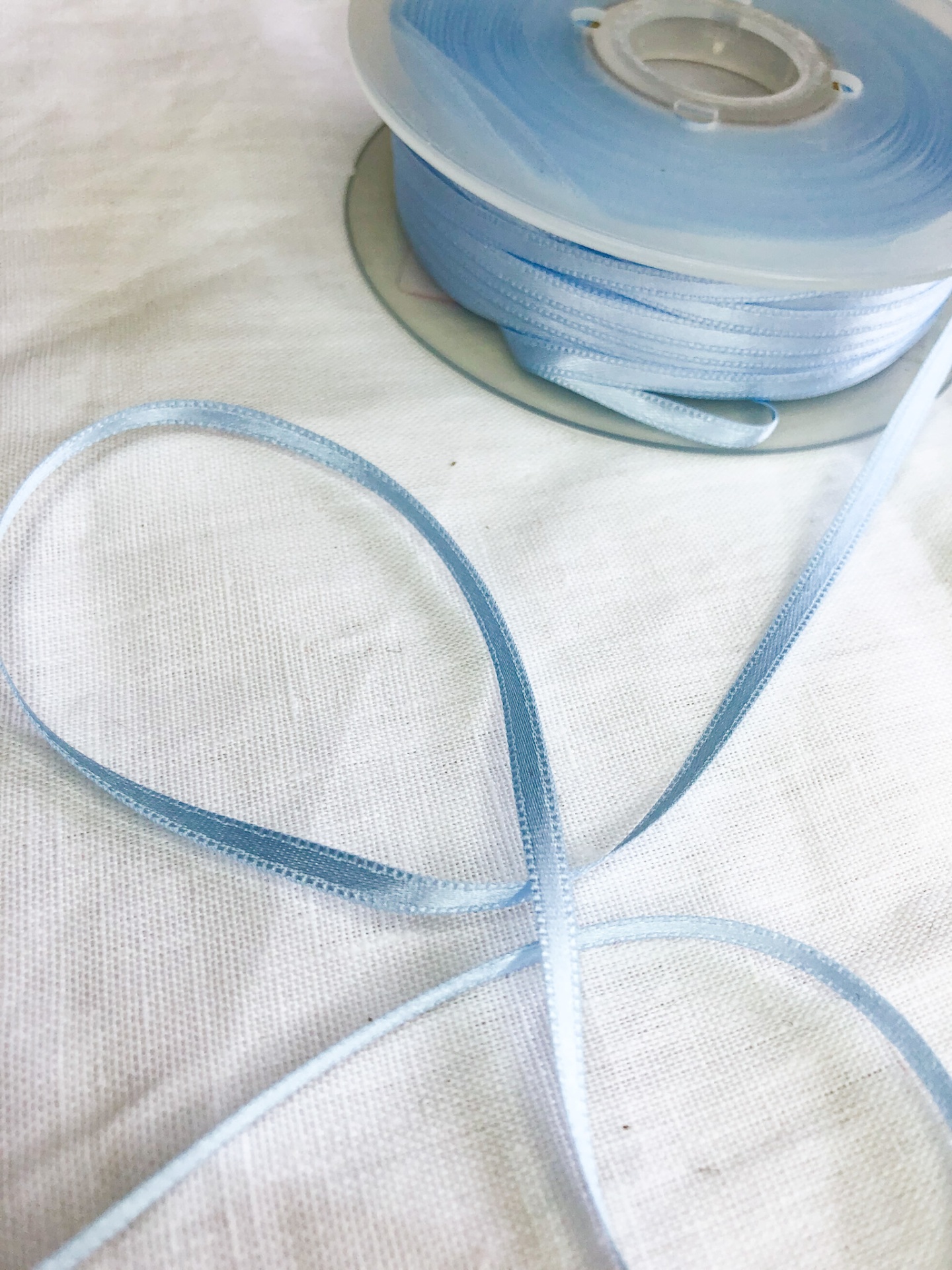fita azul clara de cetim enrolada sobre tecido branco