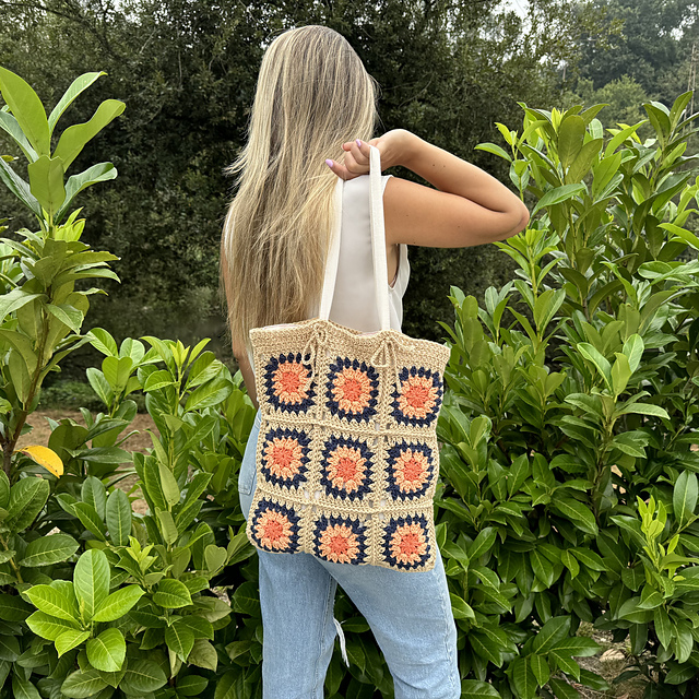 Saco de malha colorido com quadrados sendo usado ao ombro por mulher em exterior