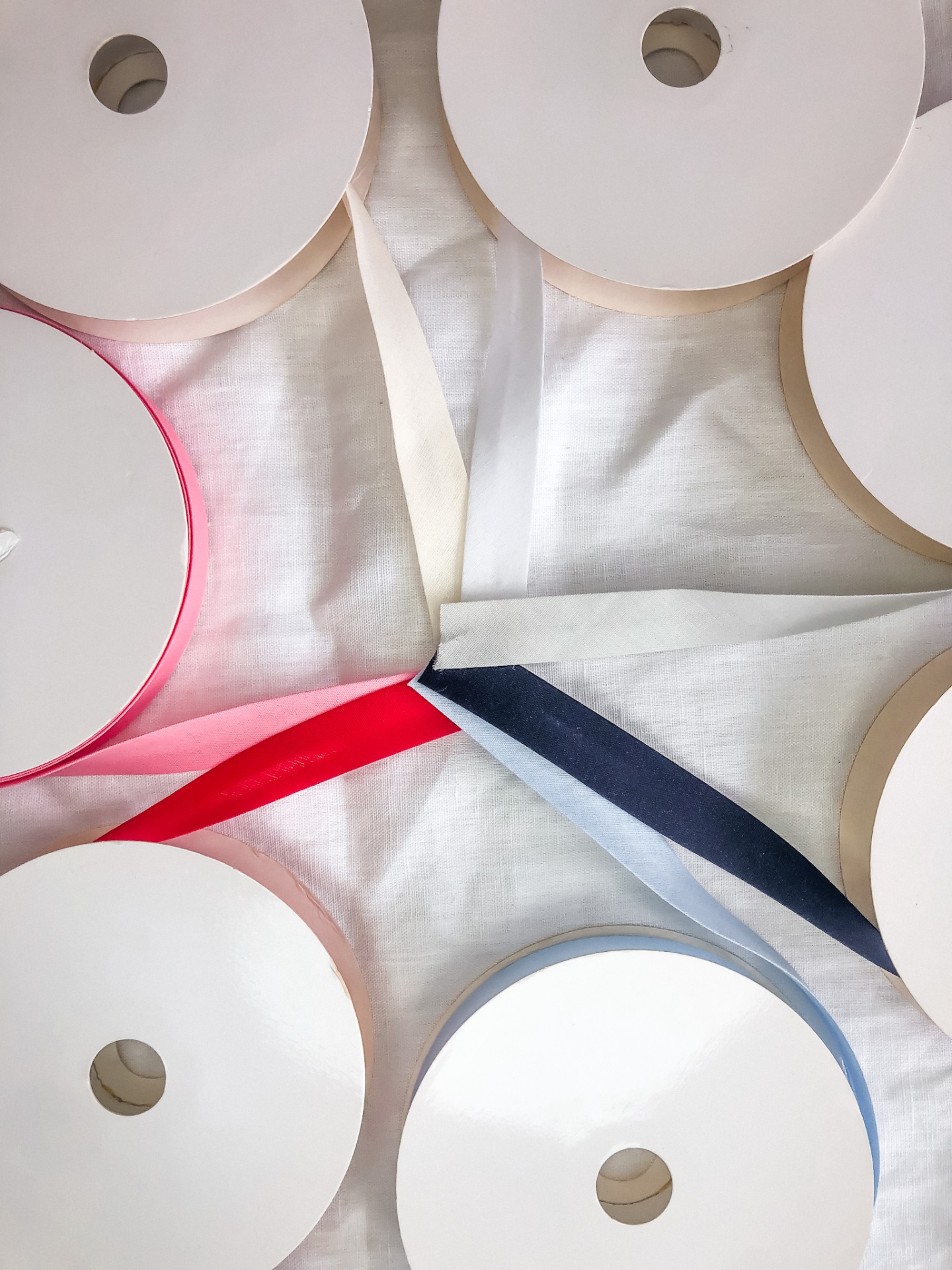 Vários rolos de fita de tecido coloridos sobre pano branco