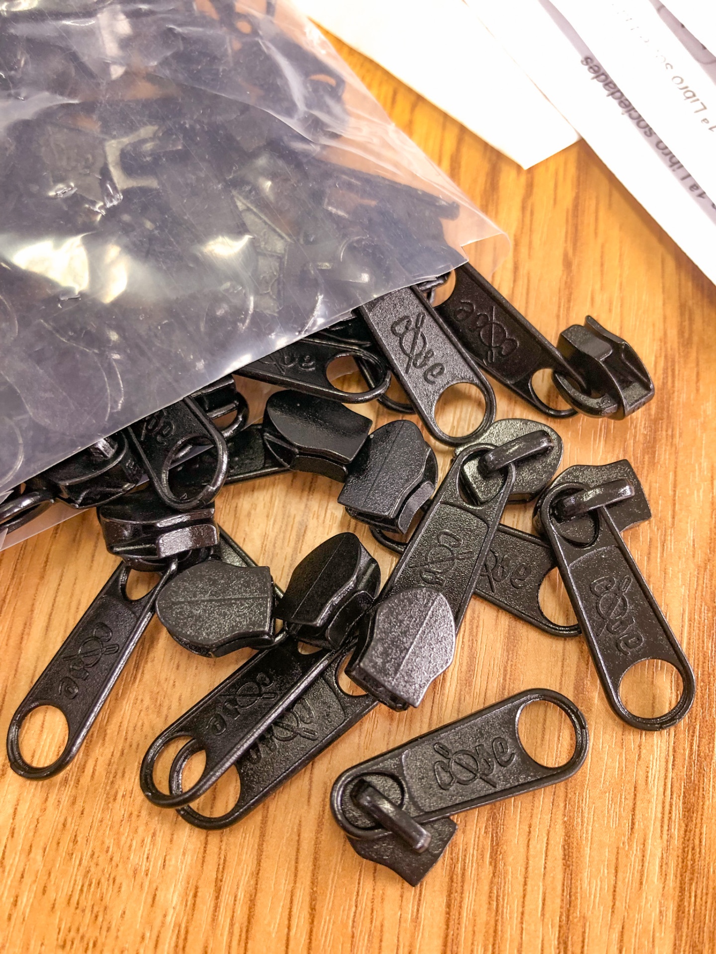 Fechos de zíper pretos com a palavra 'LOVE' gravada sobre superfície de madeira