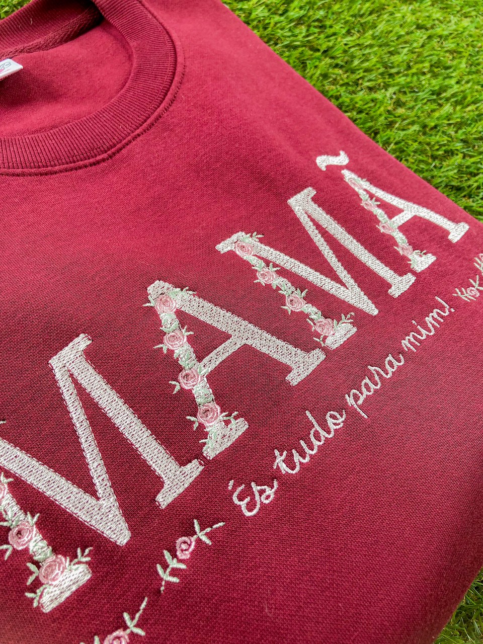 sweatshirt vermelha com bordado branco e rosas formando a palavra NAMA