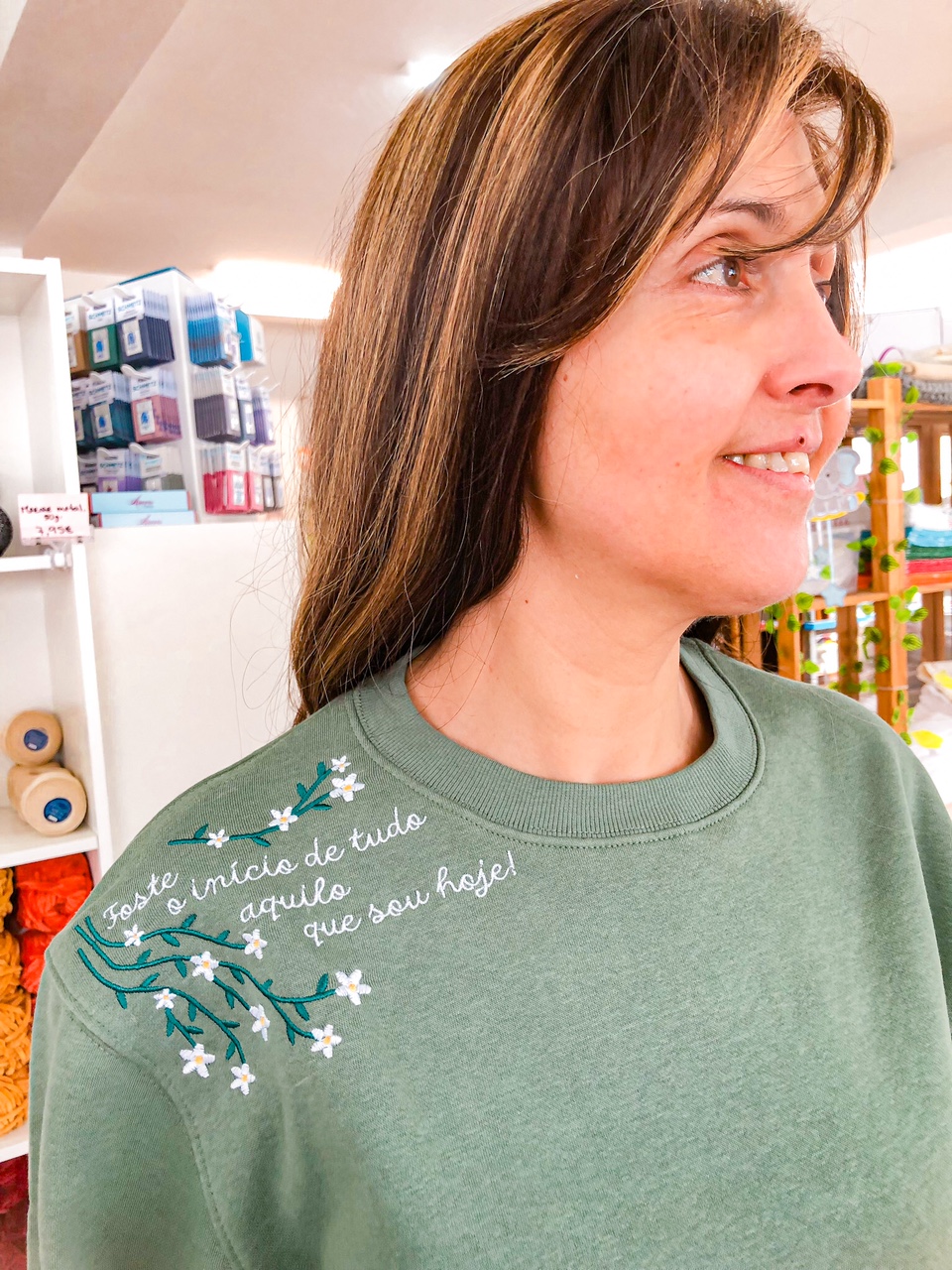 sweatshirt verde com bordado floral e texto perto do ombro esquerdo