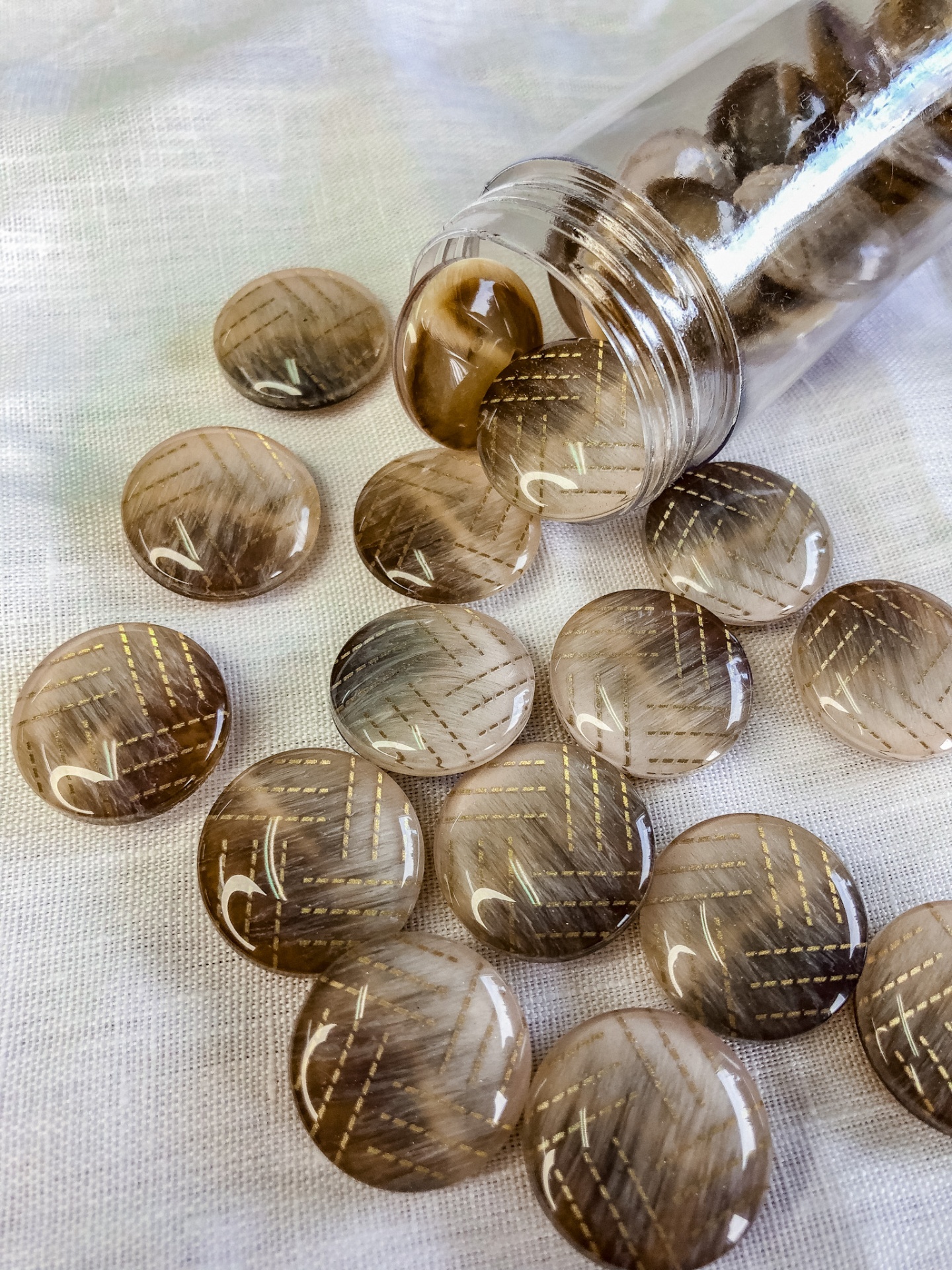 Botões redondos castanhos translúcidos com padrão dourado e número 2 sobre tecido claro
