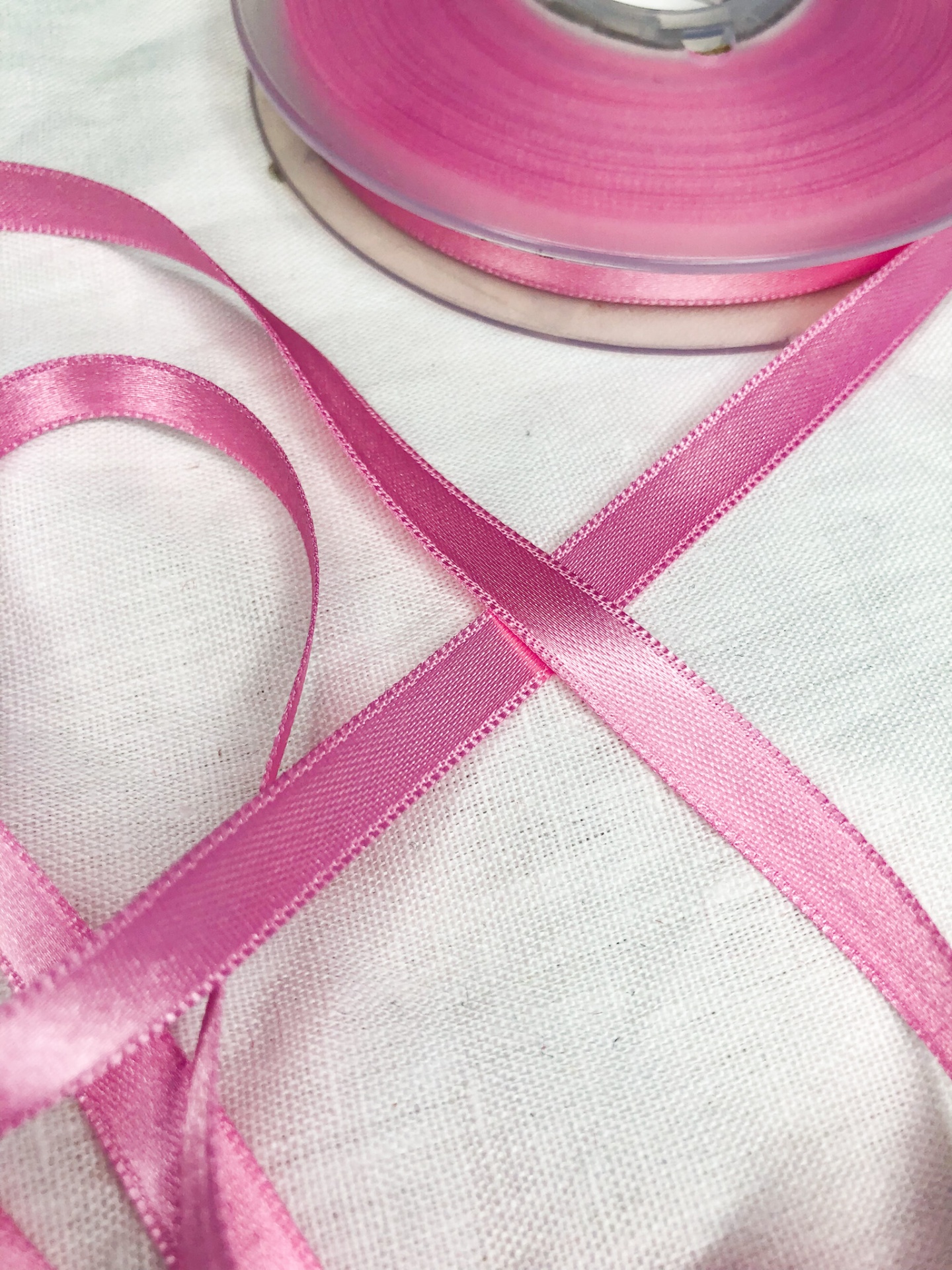 Fita de cetim rosa em rolo sobre tecido branco