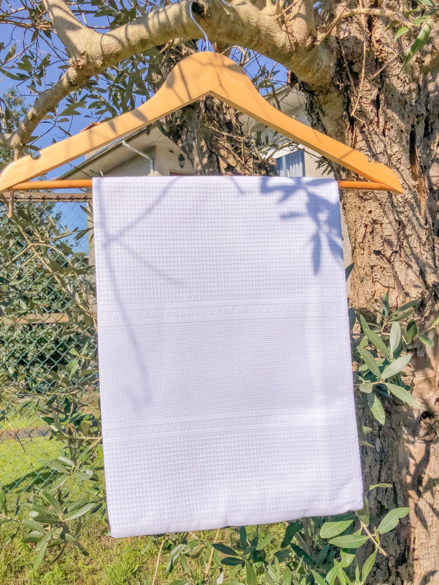 Toalha branca sobre cabide de madeira em exterior com árvores