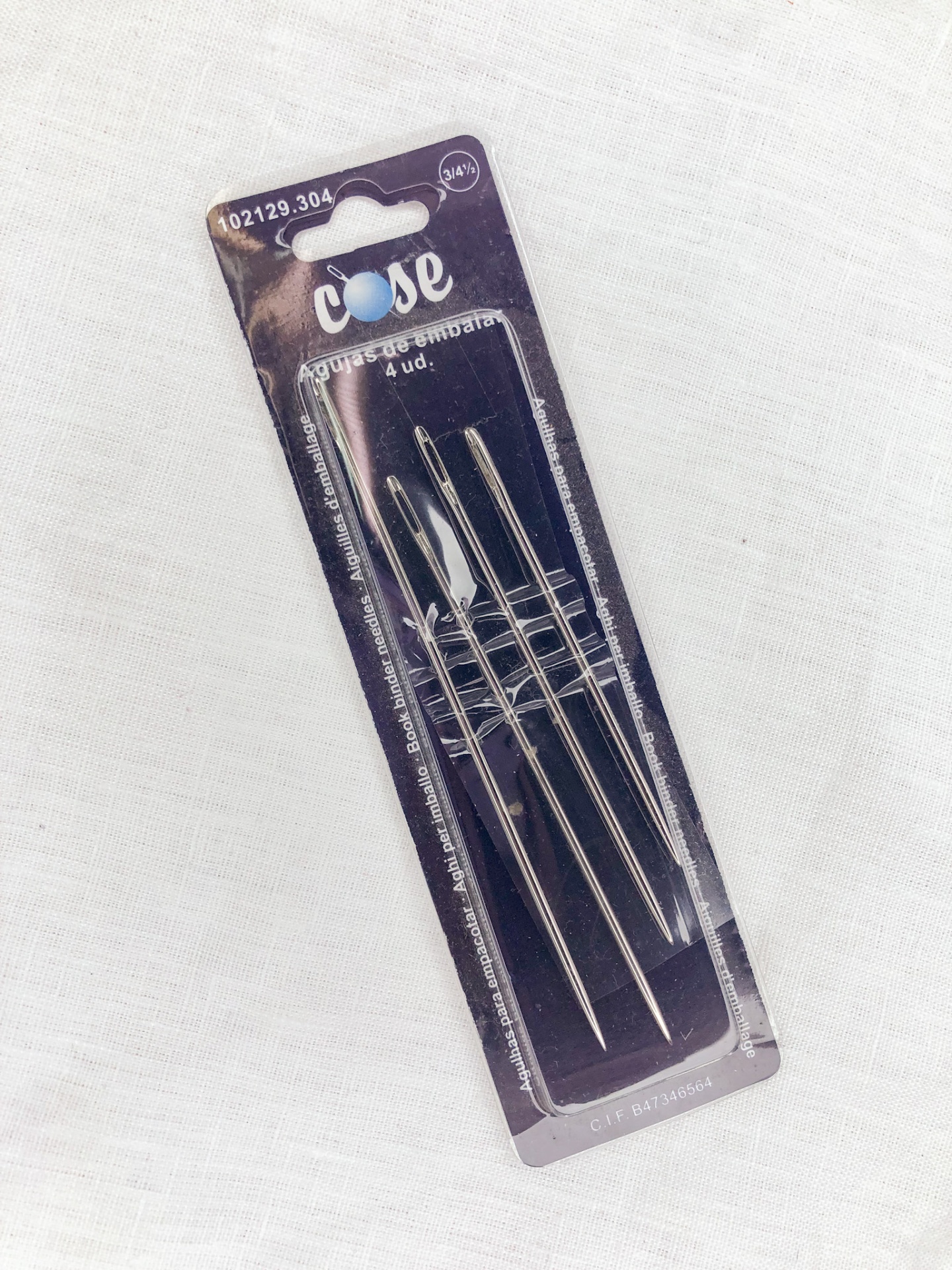 Conjunto de quatro agulhas de costura em embalagem preta com texto e código visíveis