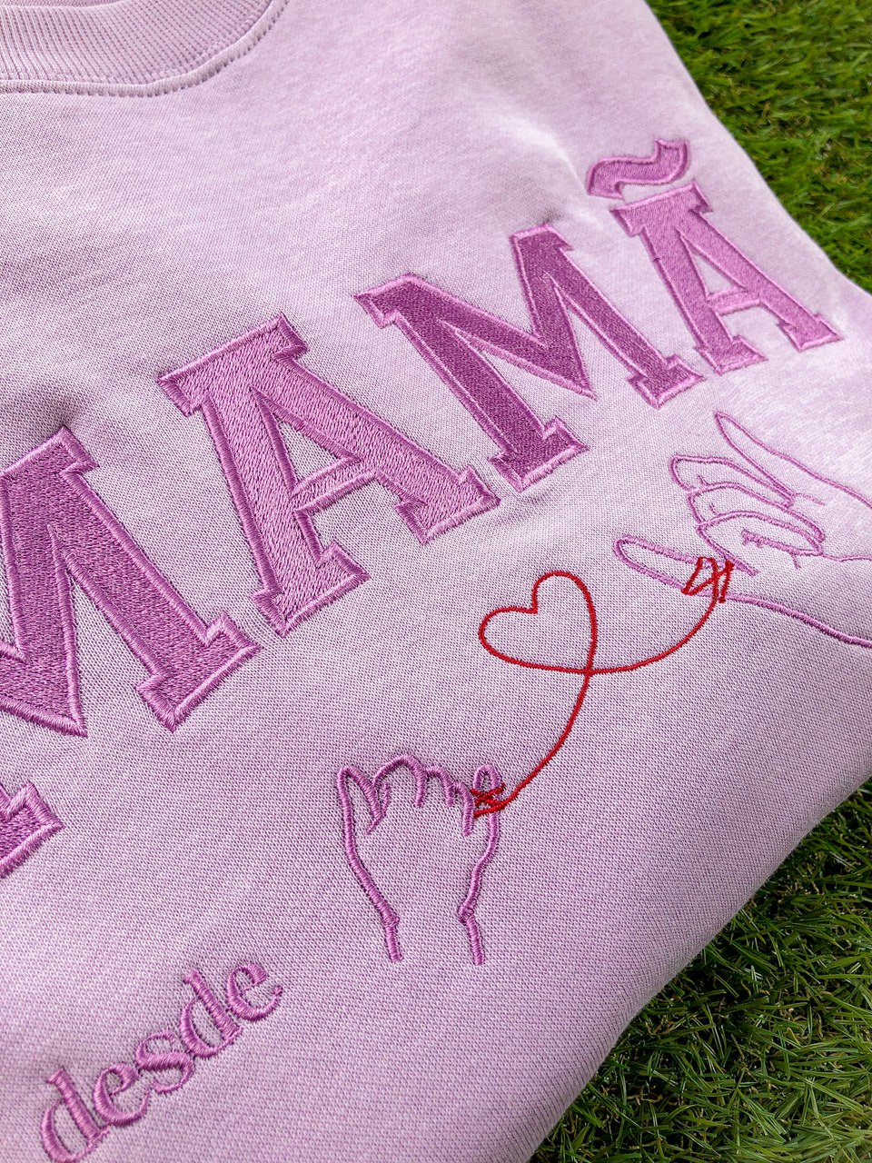 Camisola rosa com bordados cor-de-rosa e roxo e desenho de mãos com fio vermelho em formato de coração