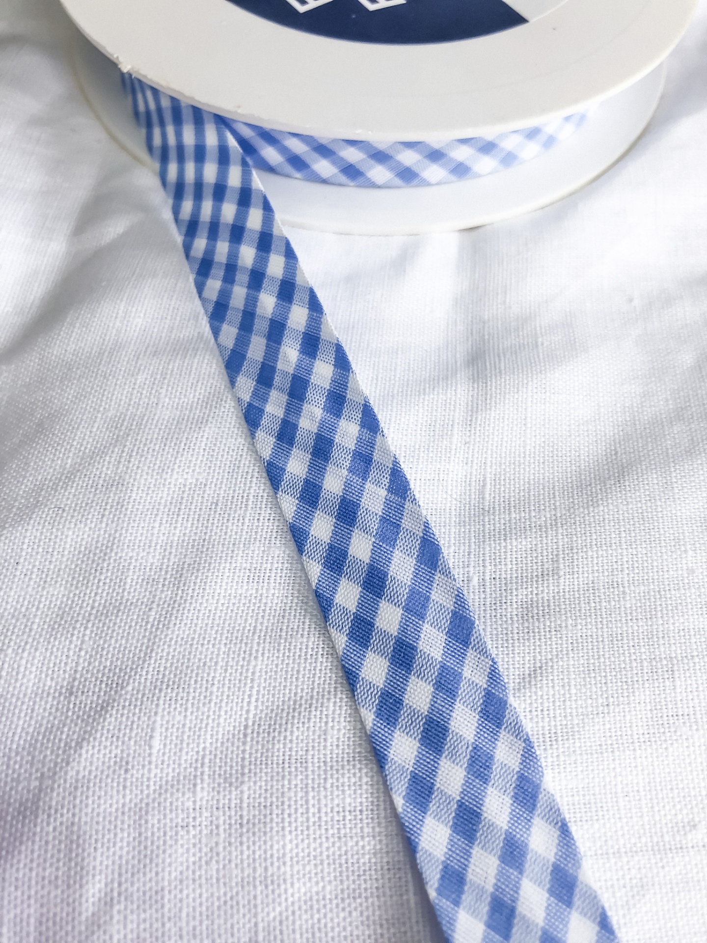 Fita xadrez azul e branca em carretel sobre tecido branco