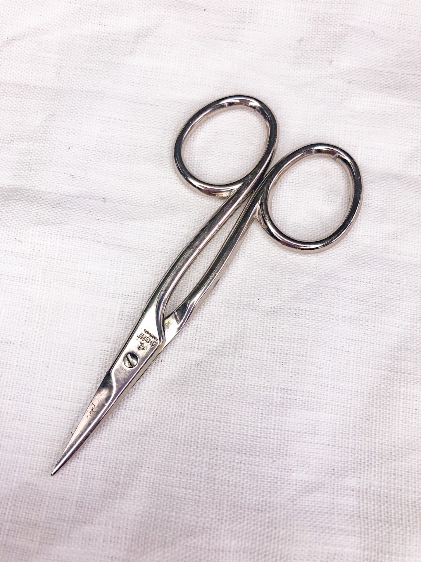 Tesoura metálica pequena sobre tecido branco