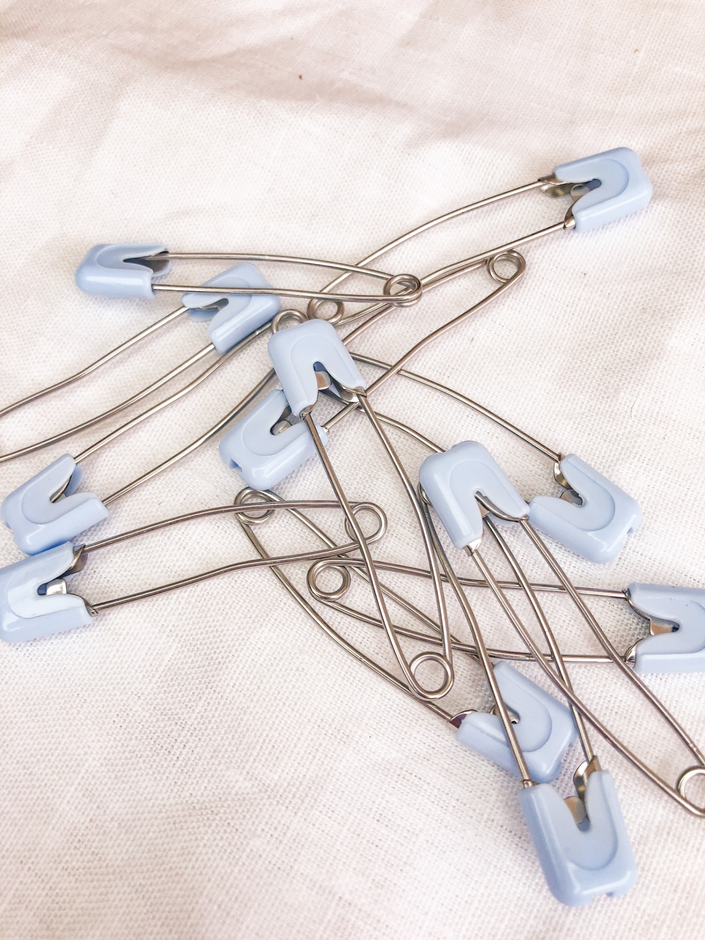 Alfinetes de ama com cabeça azul clara sobre tecido branco