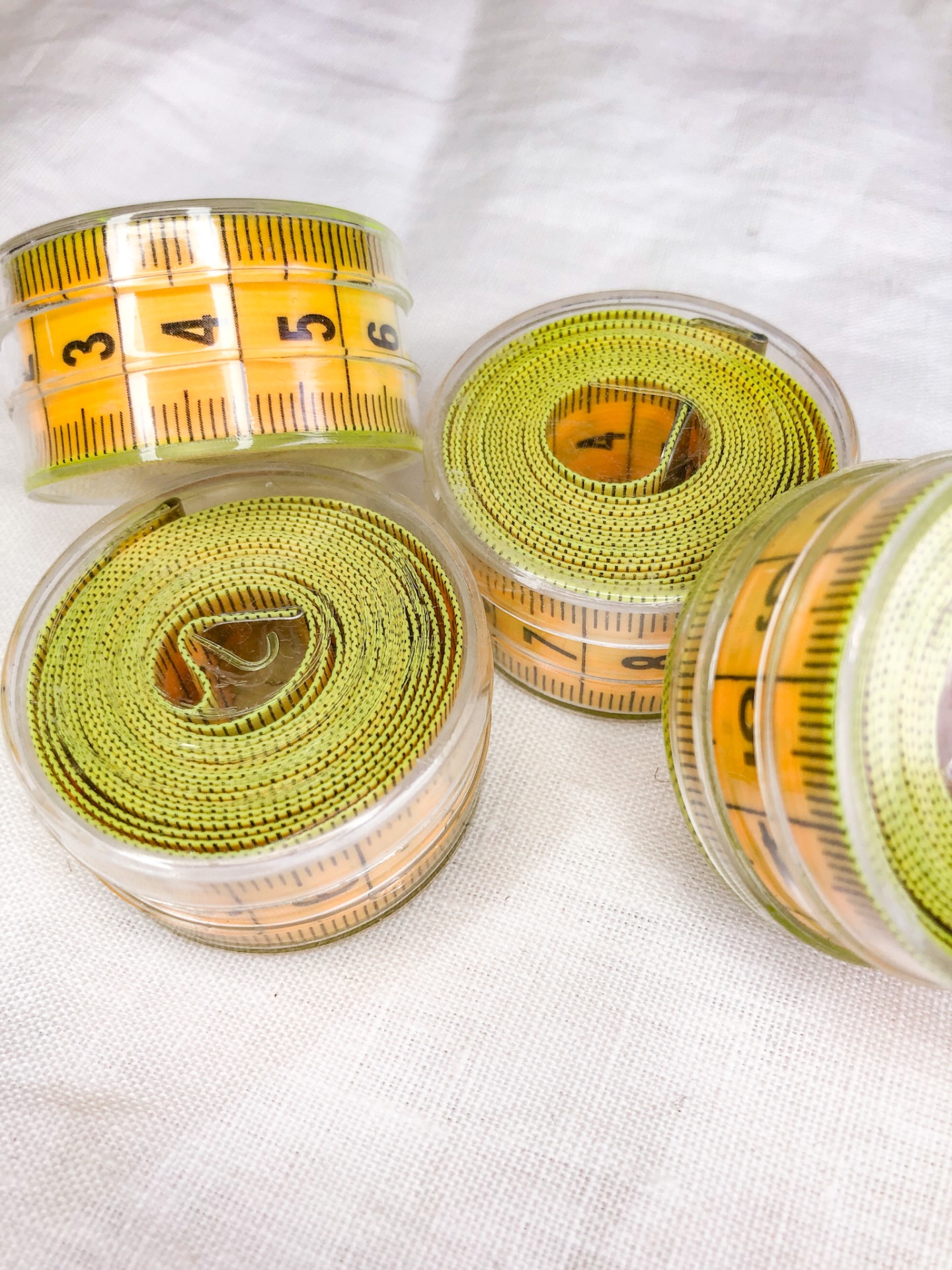 Fitas métricas amarelas em caixas transparentes sobre tecido branco