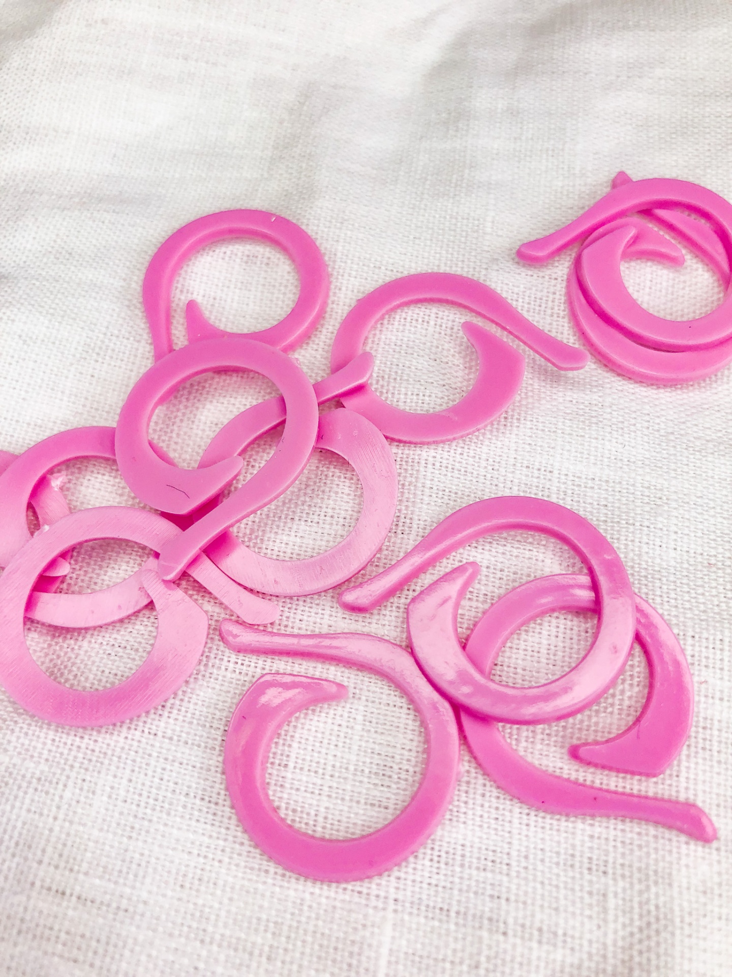 Anéis plásticos cor-de-rosa com gancho sobre tecido branco
