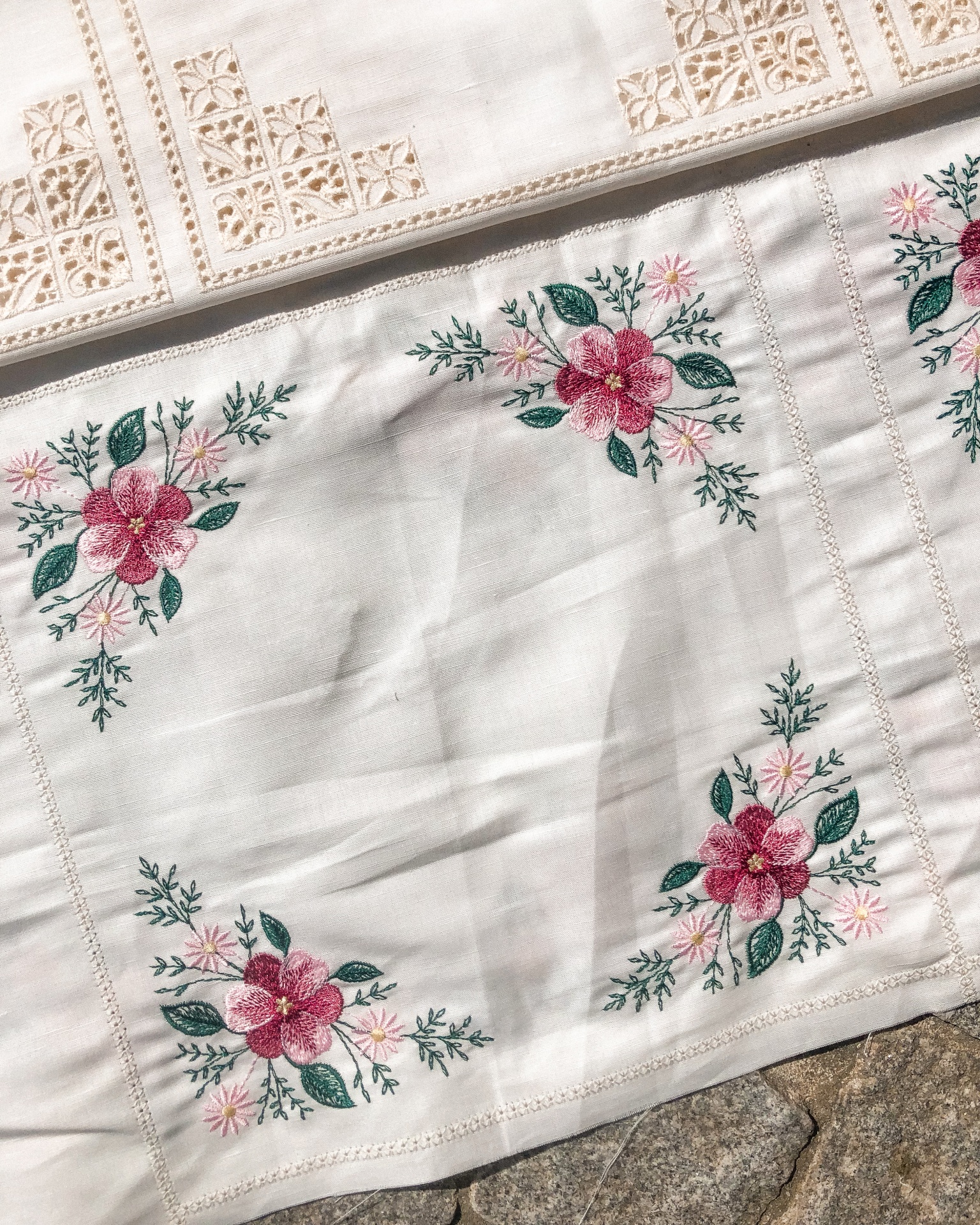 Toalha branca com bordado floral colorido nos cantos.