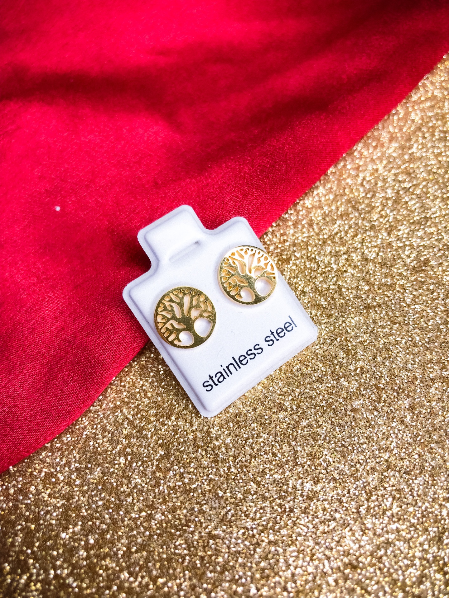 Brincos de aço inoxidável em forma de árvore dourada sobre suporte branco