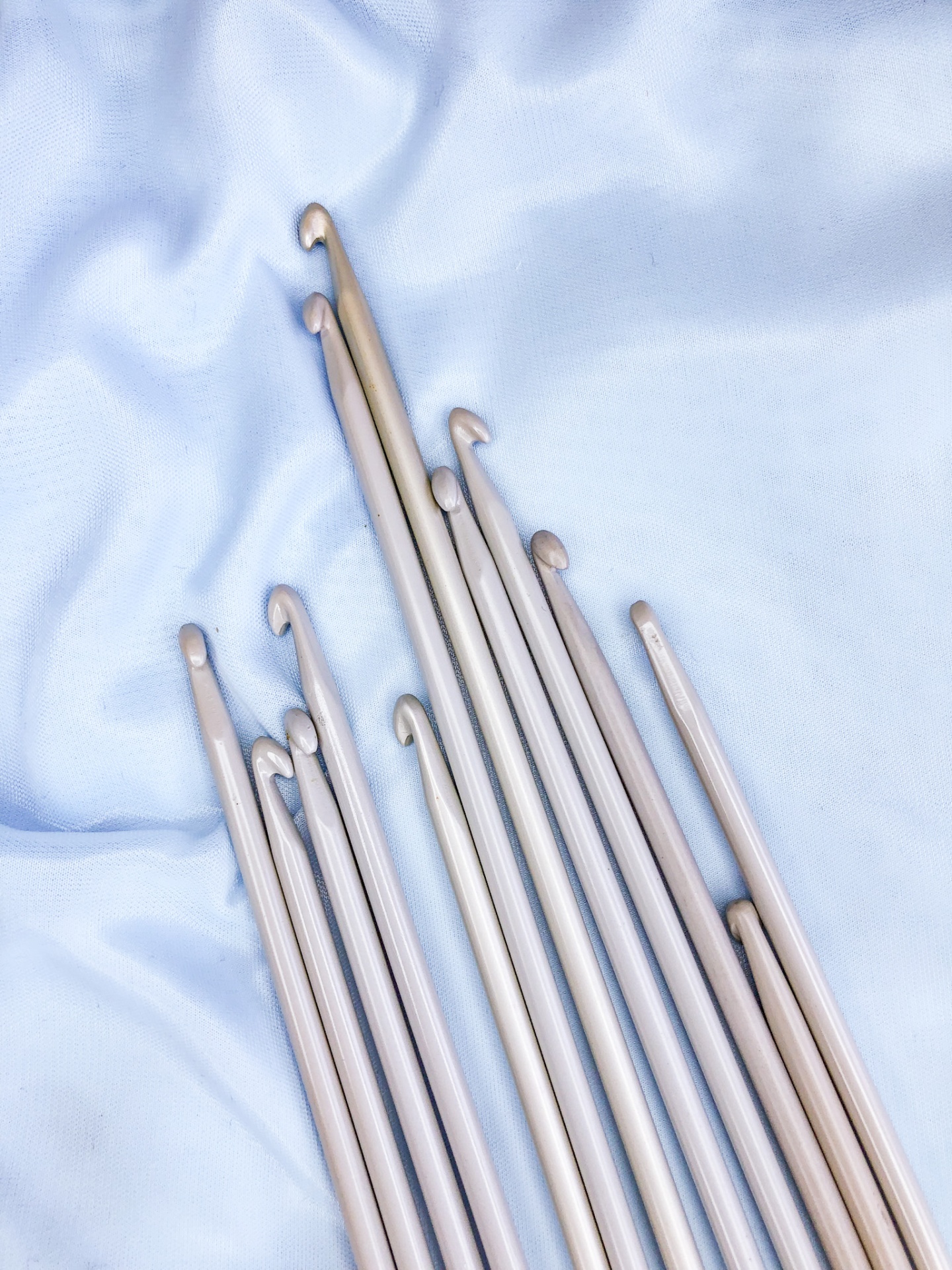 Agulhas de tricô de alumínio prateadas sobre tecido azul claro