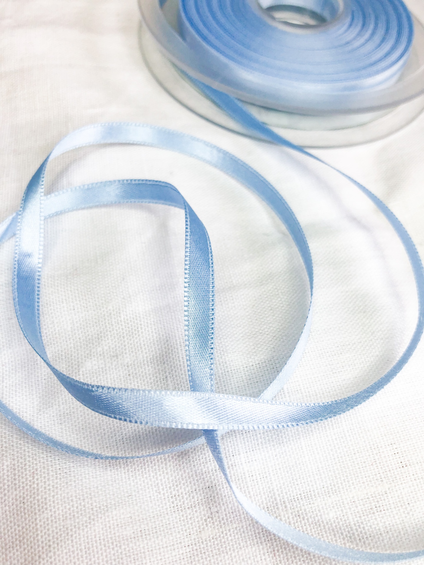 Fita azul clara acetinada em rolo sobre tecido branco
