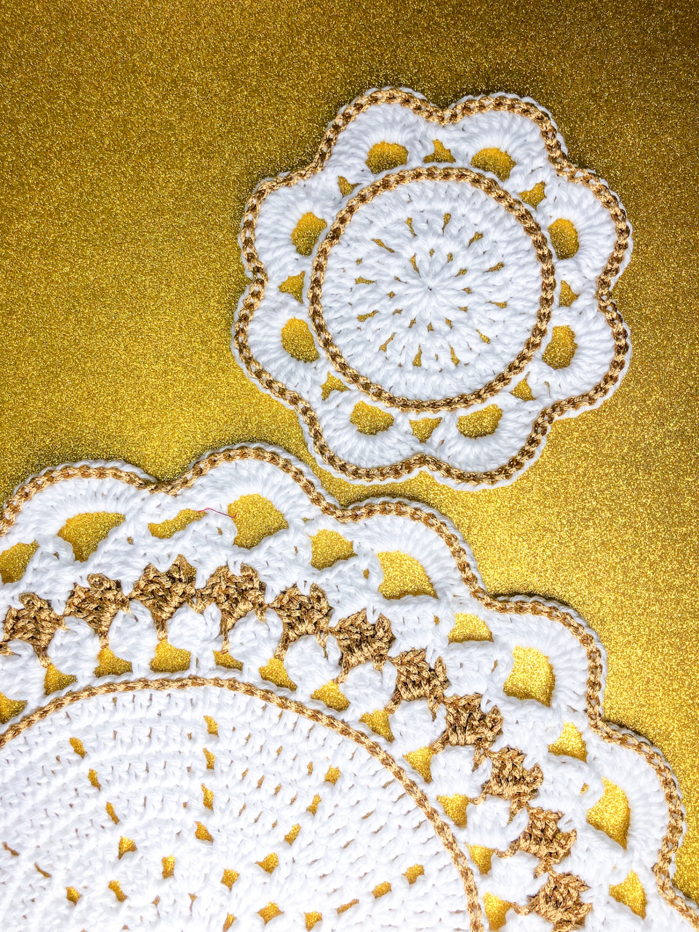 Trabalhos de crochet redondos brancos e dourados sobre fundo dourado brilhante