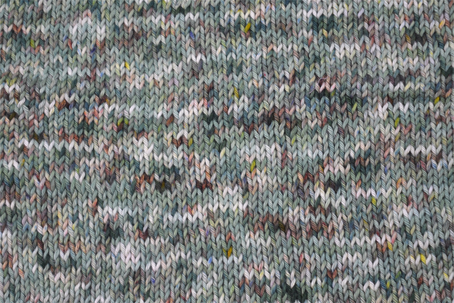 Tecido de malha cinza com fios multicoloridos e padrão tricotado irregular