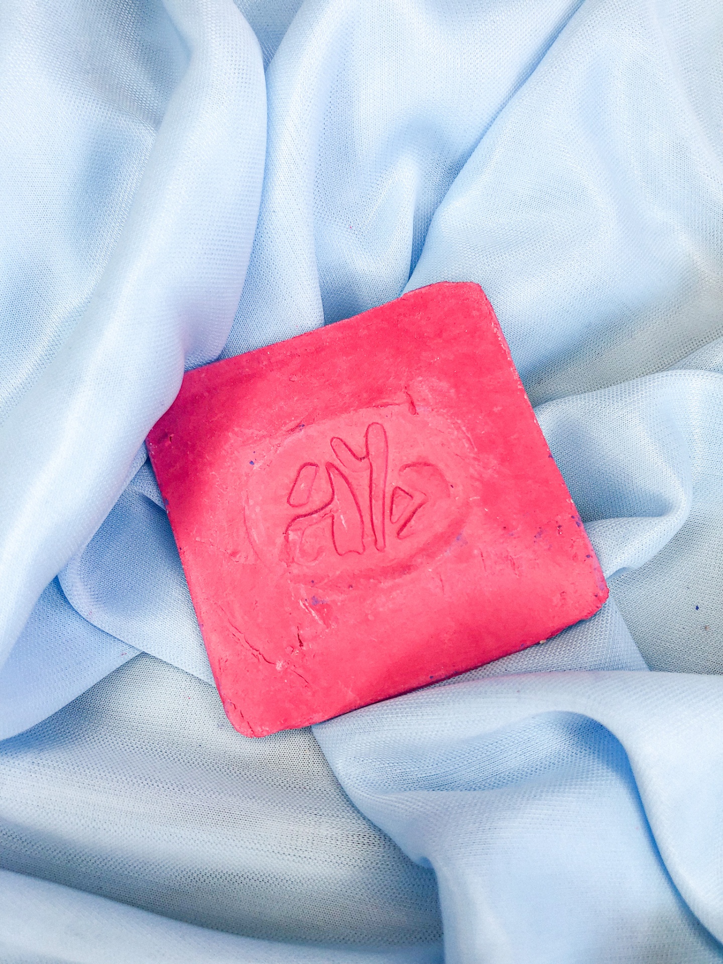 Sabão sólido quadrado rosa em tecido azul claro