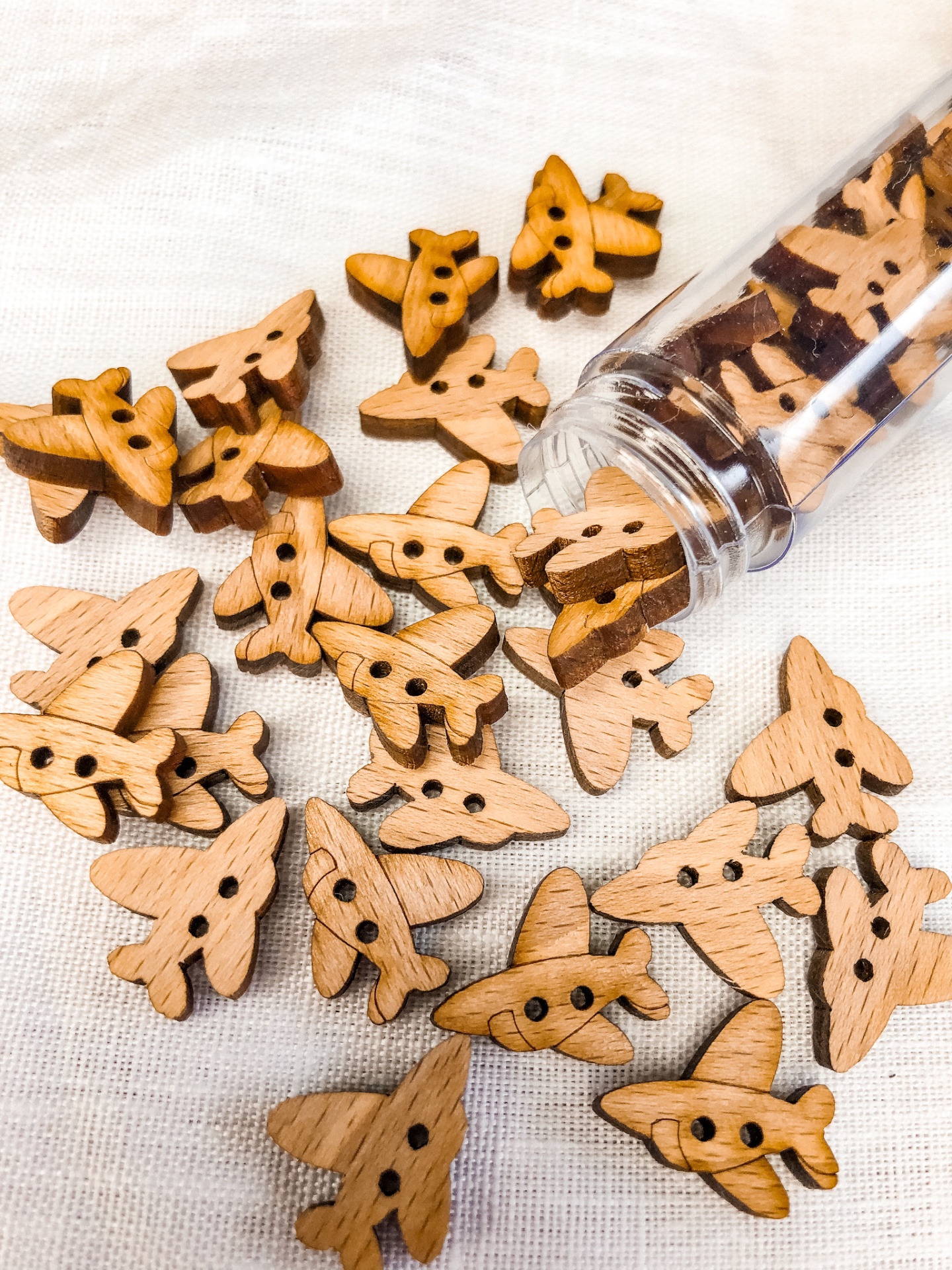 Botões de madeira em forma de avião sobre tecido branco