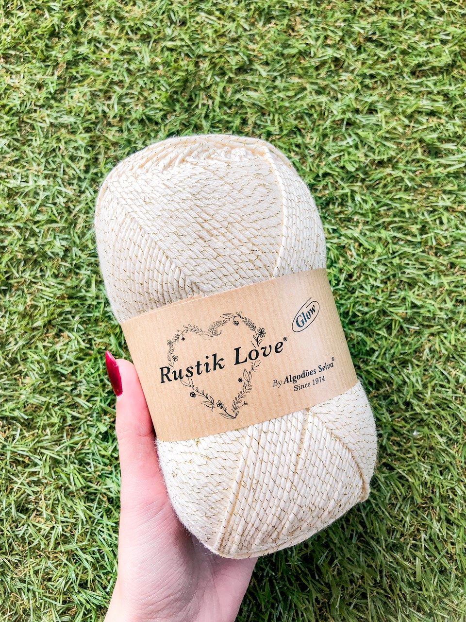 Novelo de fio macramé bege com fios dourados e etiqueta Rustik Love.