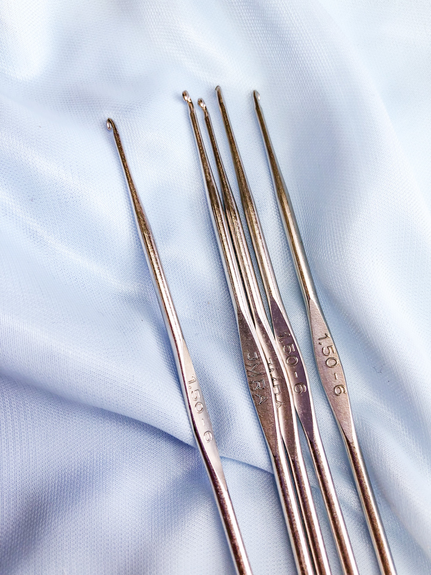 agulhas de crochet metálicas prateadas sobre tecido azul claro
