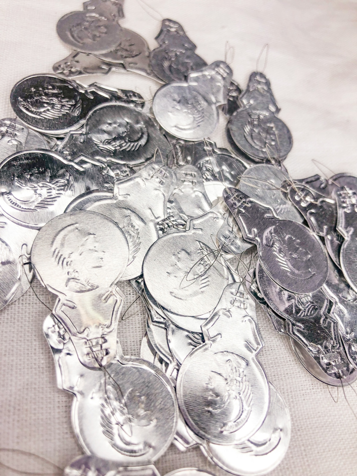 Pendentes metálicos prateados com desenhos em relevo sobre superfície clara