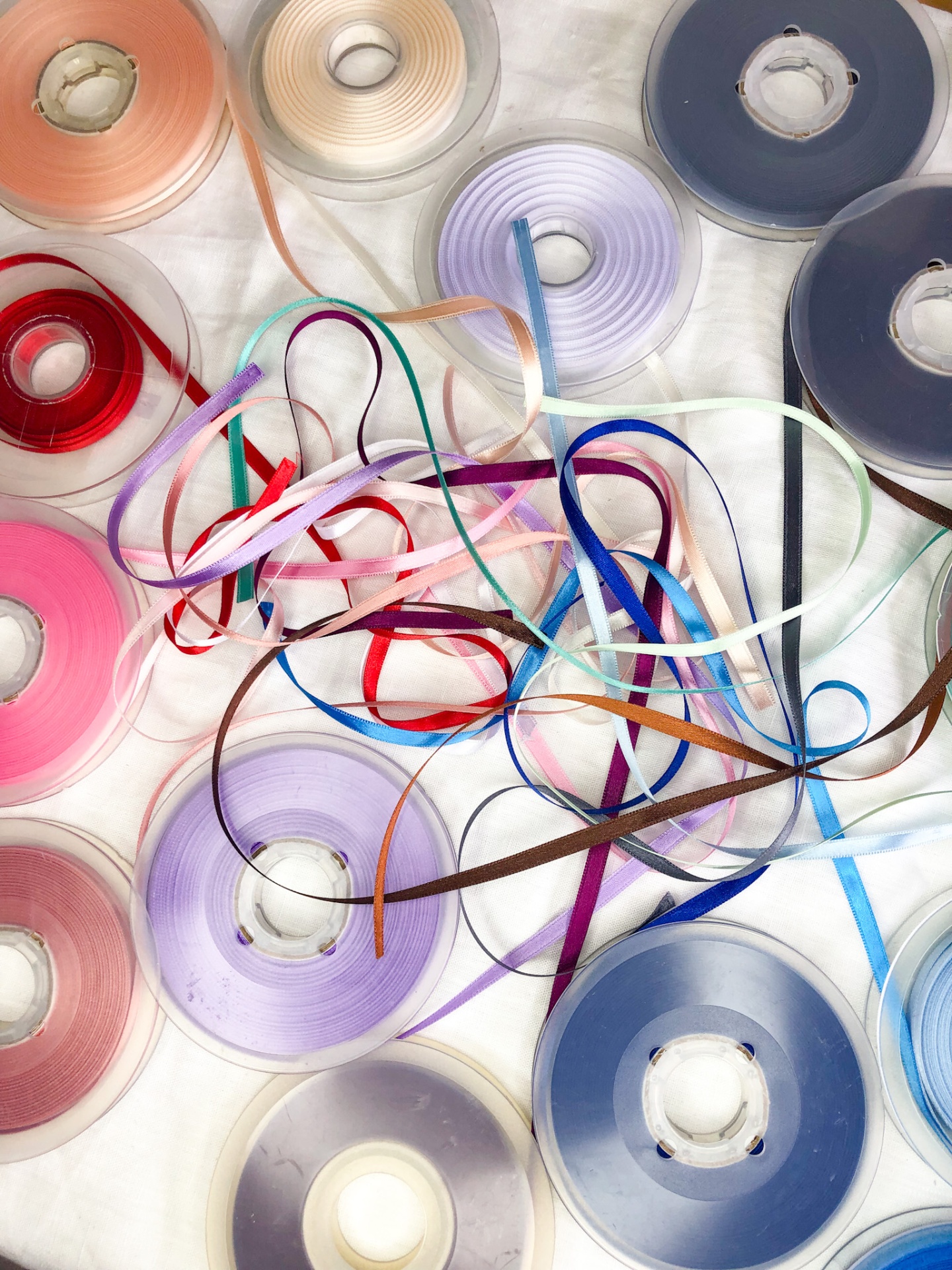 Várias bobinas de fita colorida sobre superfície branca com fitas soltas entrelaçadas