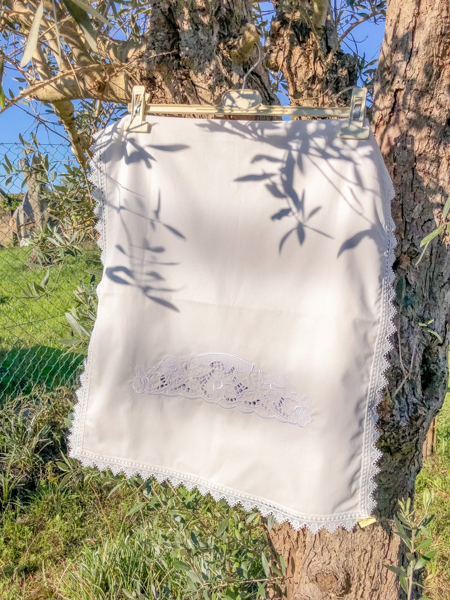 Saia branca com renda pendurada numa árvore ao ar livre
