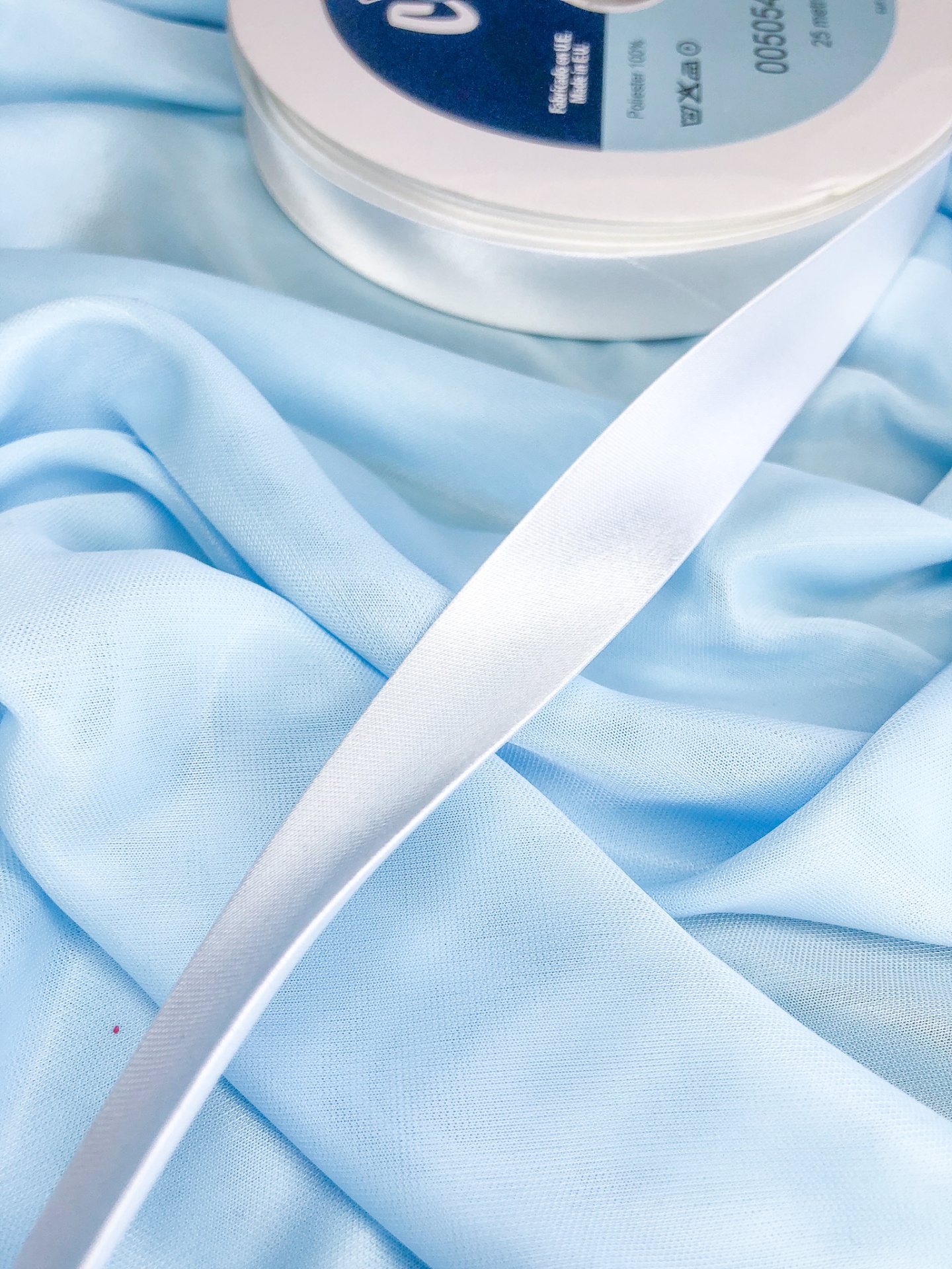 Fita branca satinada sobre tecido azul claro
