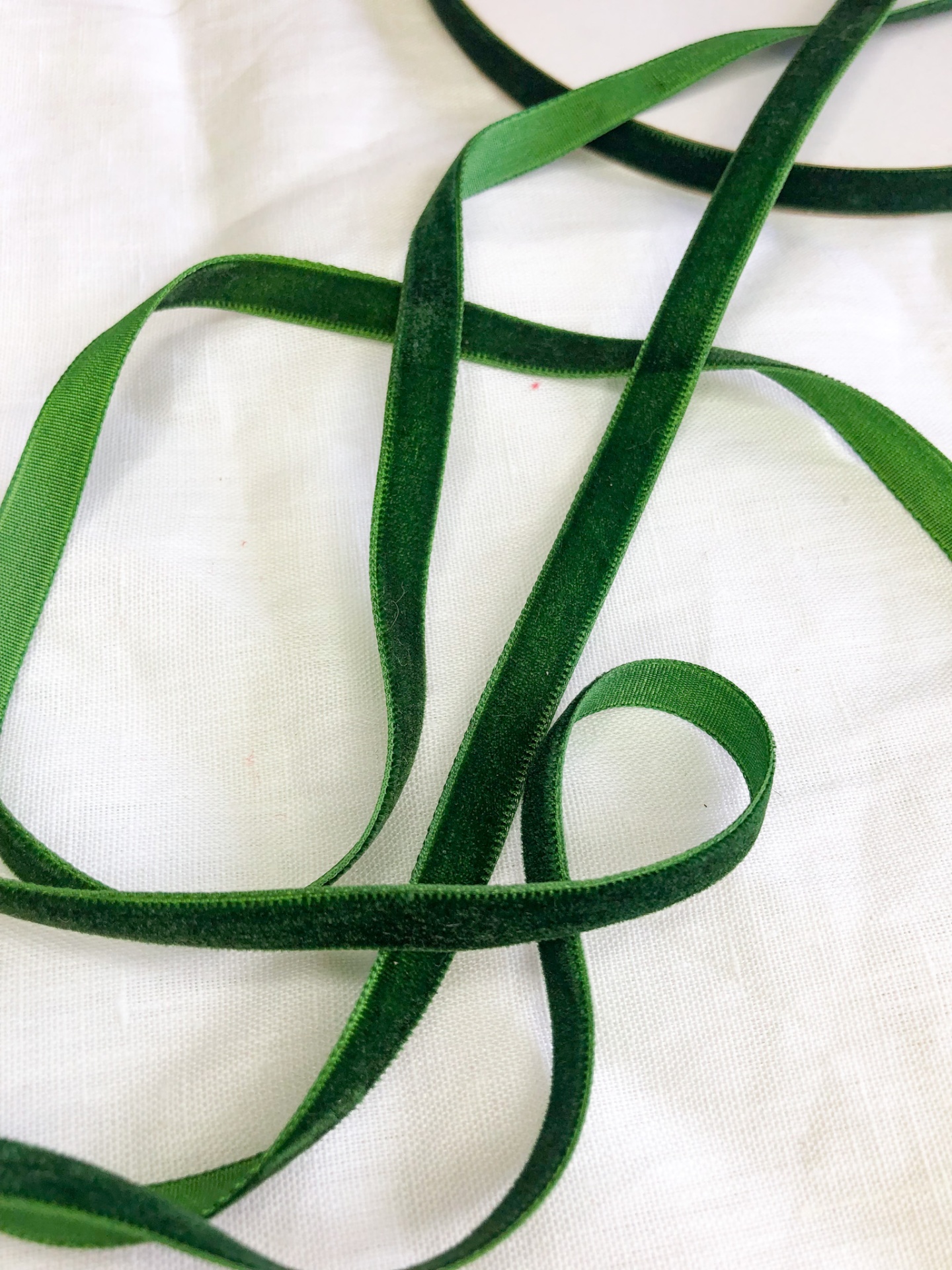Fita de veludo verde escuro sobre tecido branco