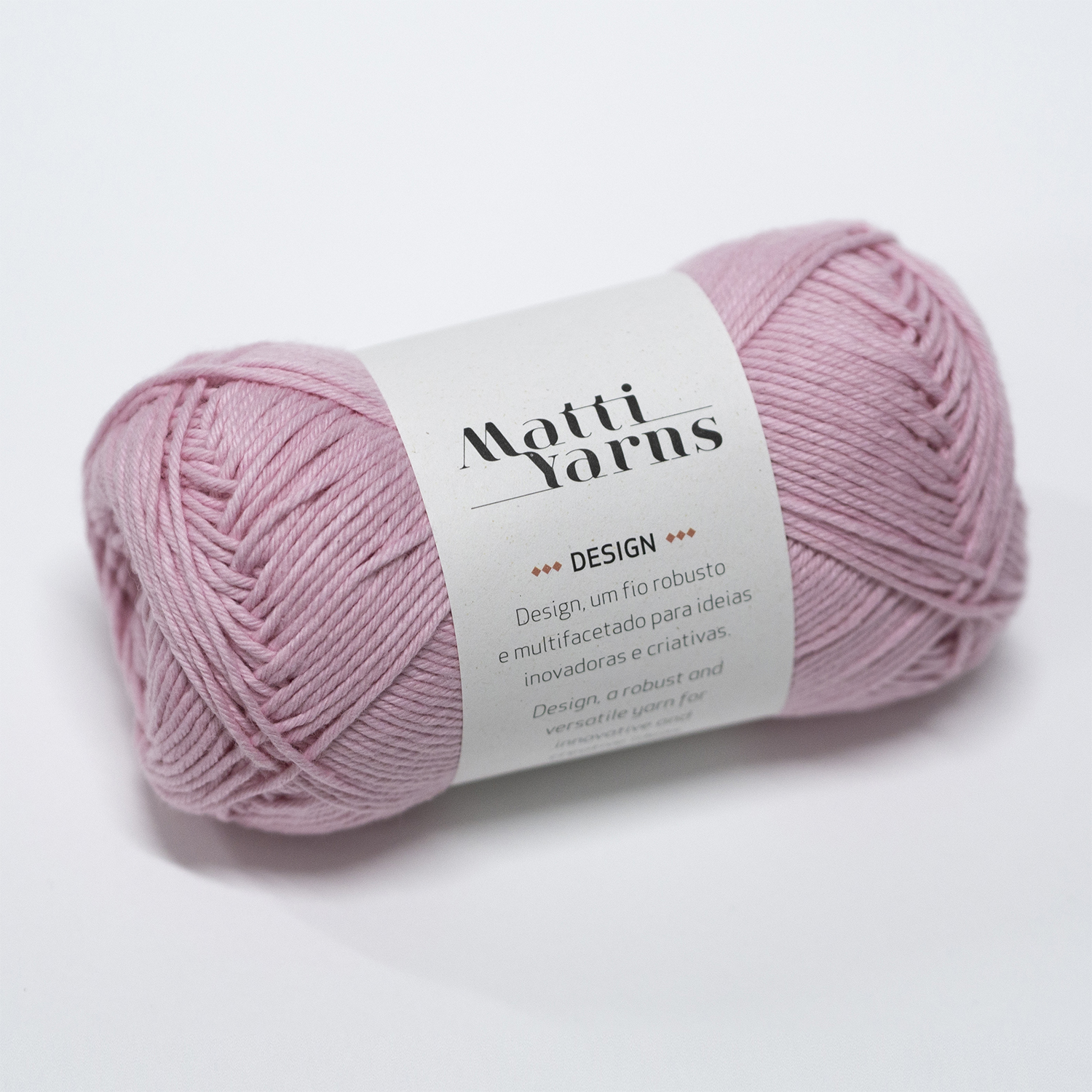Novelo de fio rosa claro com etiqueta branca da marca Matti Yarns sobre fundo branco