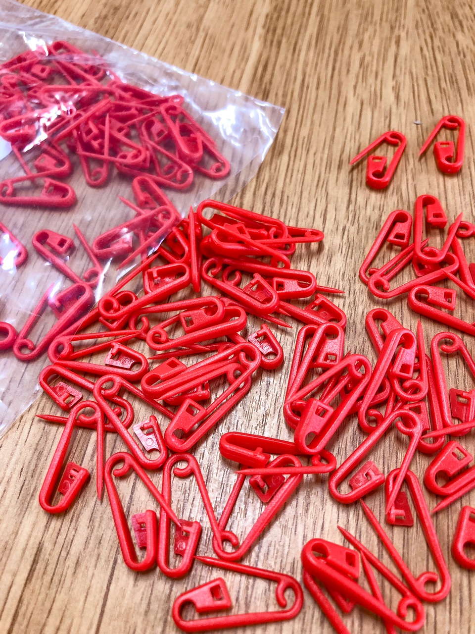 Alfinetes de segurança vermelhos de plástico em superfície de madeira