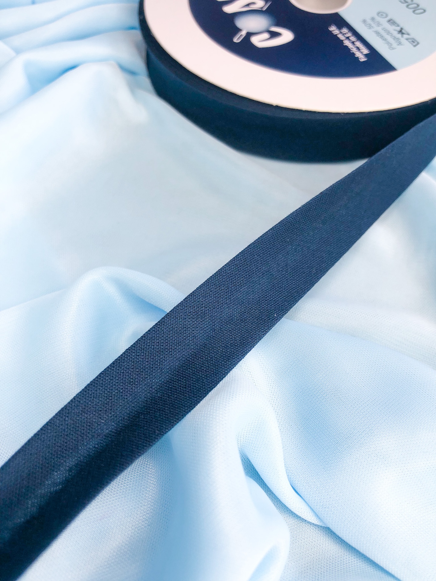 Fita azul escura em rolo com etiqueta sobre tecido azul claro