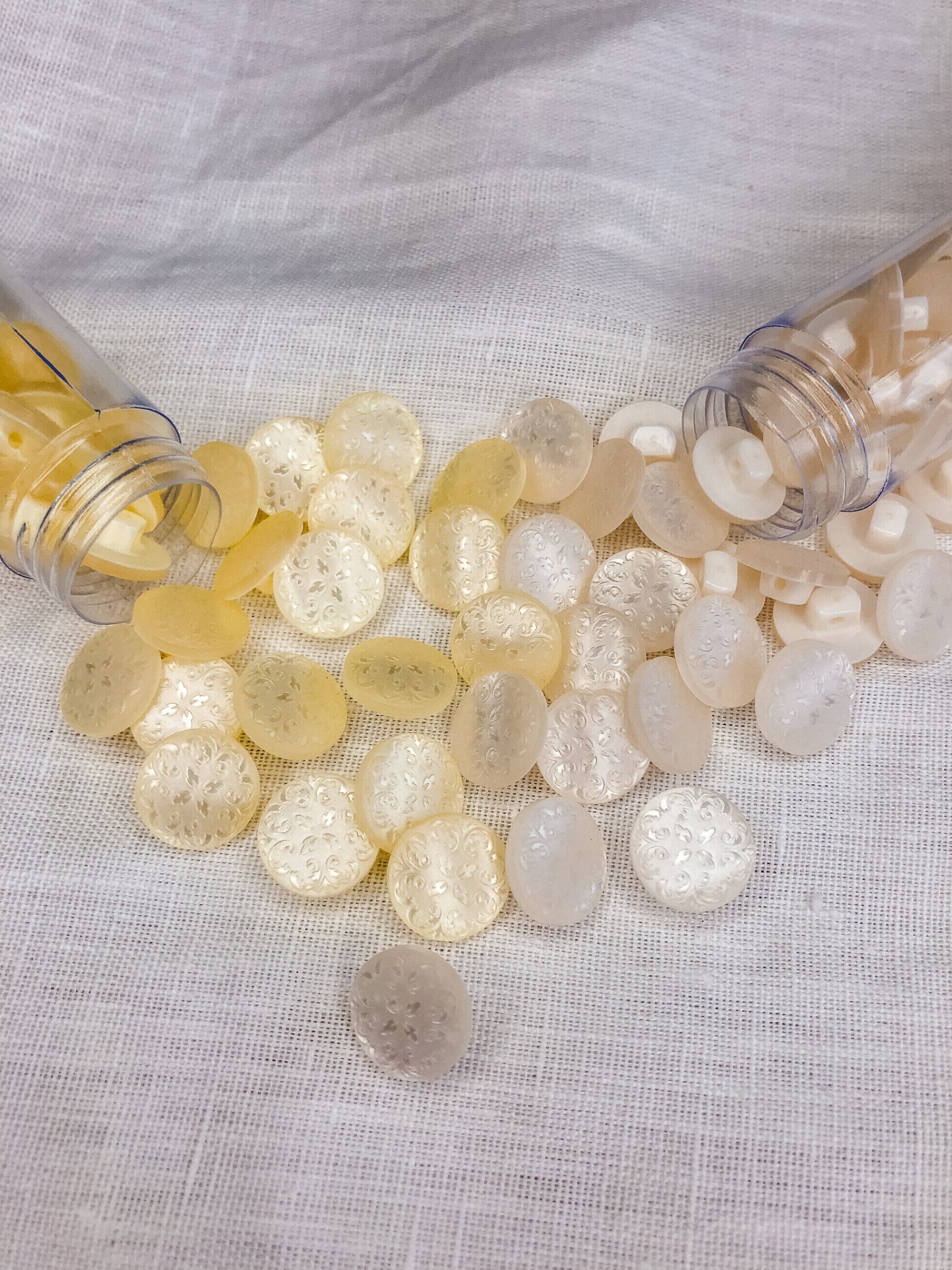 Botões transparentes e amarelos sobre tecido branco com frascos plásticos