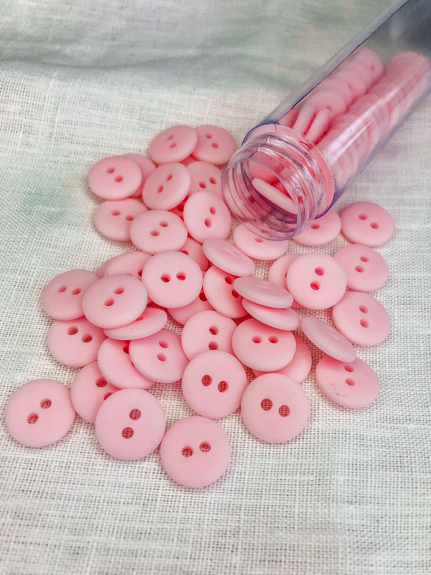 Botões rosa em tubo transparente sobre tecido branco