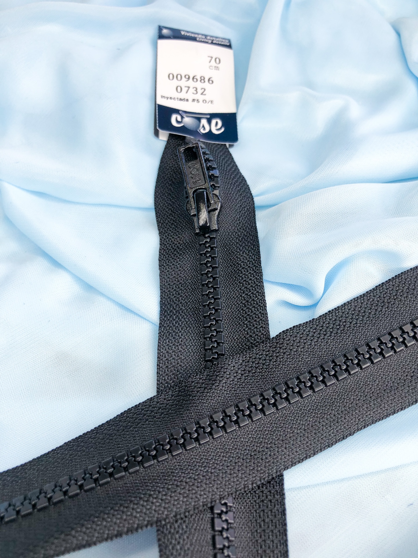 Fecho éclair preto sobre tecido azul claro com etiqueta