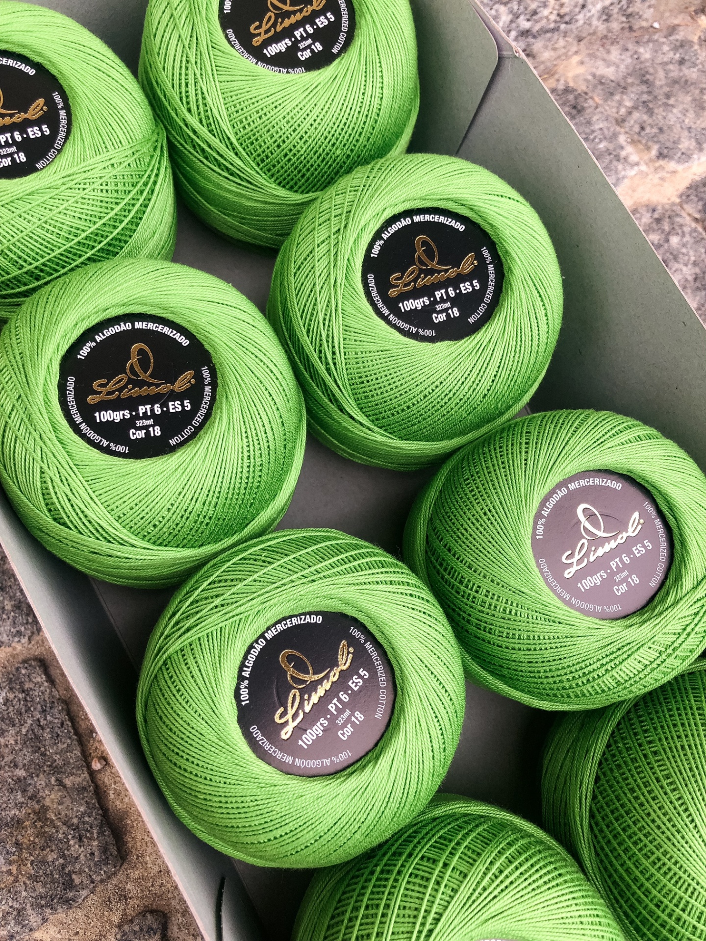 Novelos de linha de algodão mercerizado verde claro numa caixa cinzenta