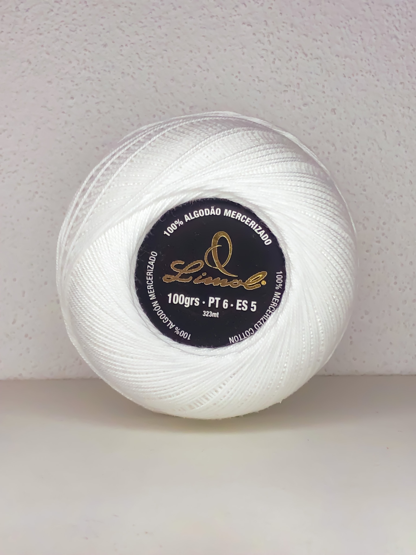 Rolo de linha branco de algodão mercerizado com etiqueta preta e texto branco e dourado