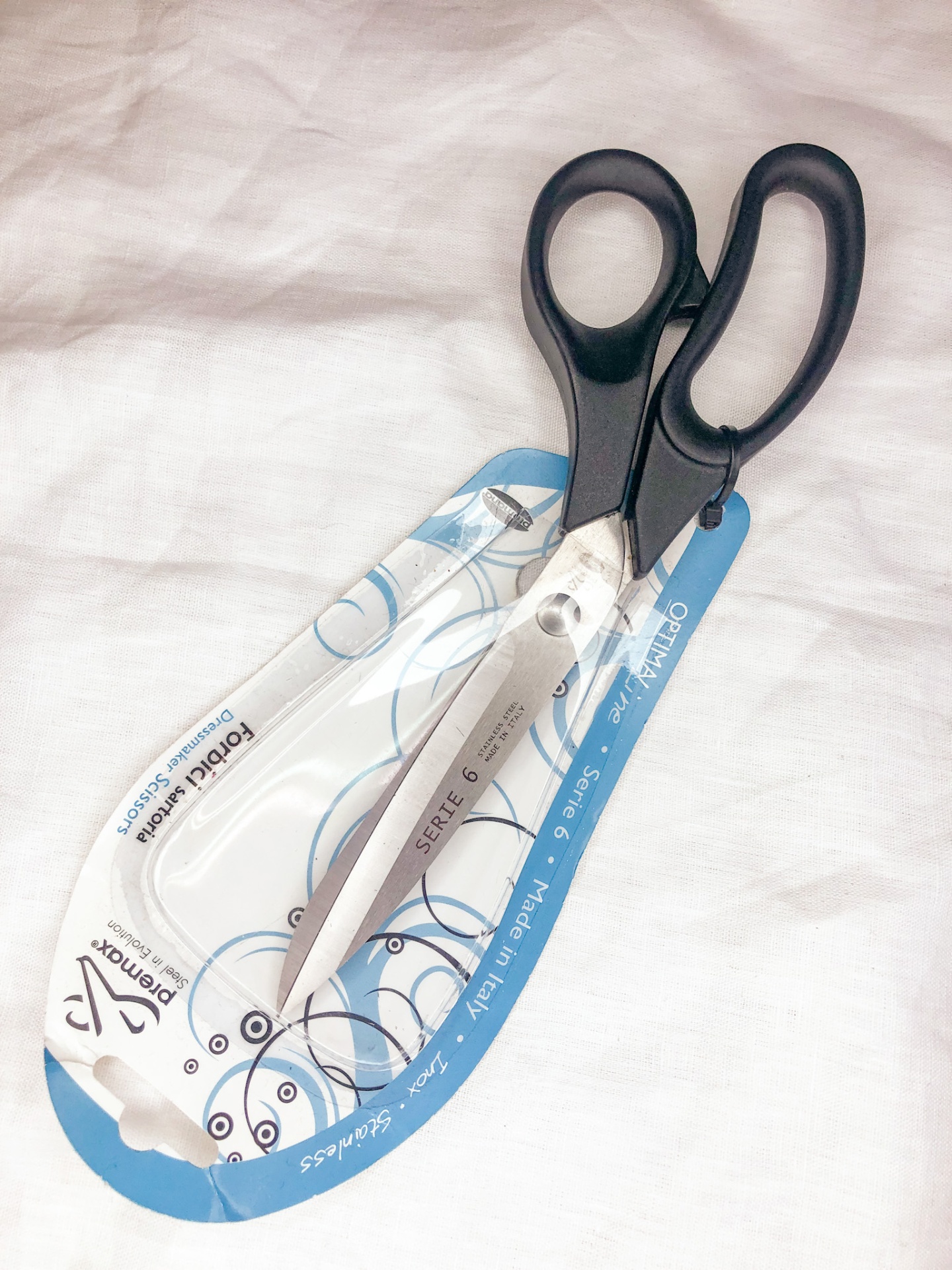 Tesoura de cortar com lâminas em aço inoxidável e cabos pretos em embalagem de cartão branca e azul